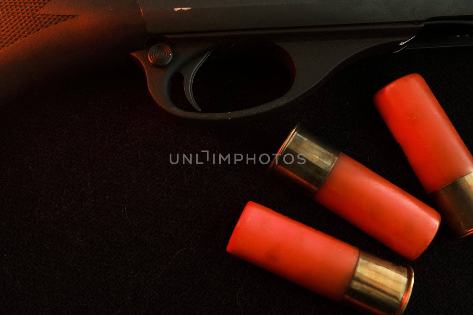 Trigger of a rifle on black background with red lightning with Shotgun shells on a black surface. Ammunition for 12 gauge smoothbore weapons. Hunting ammunition. Dark background