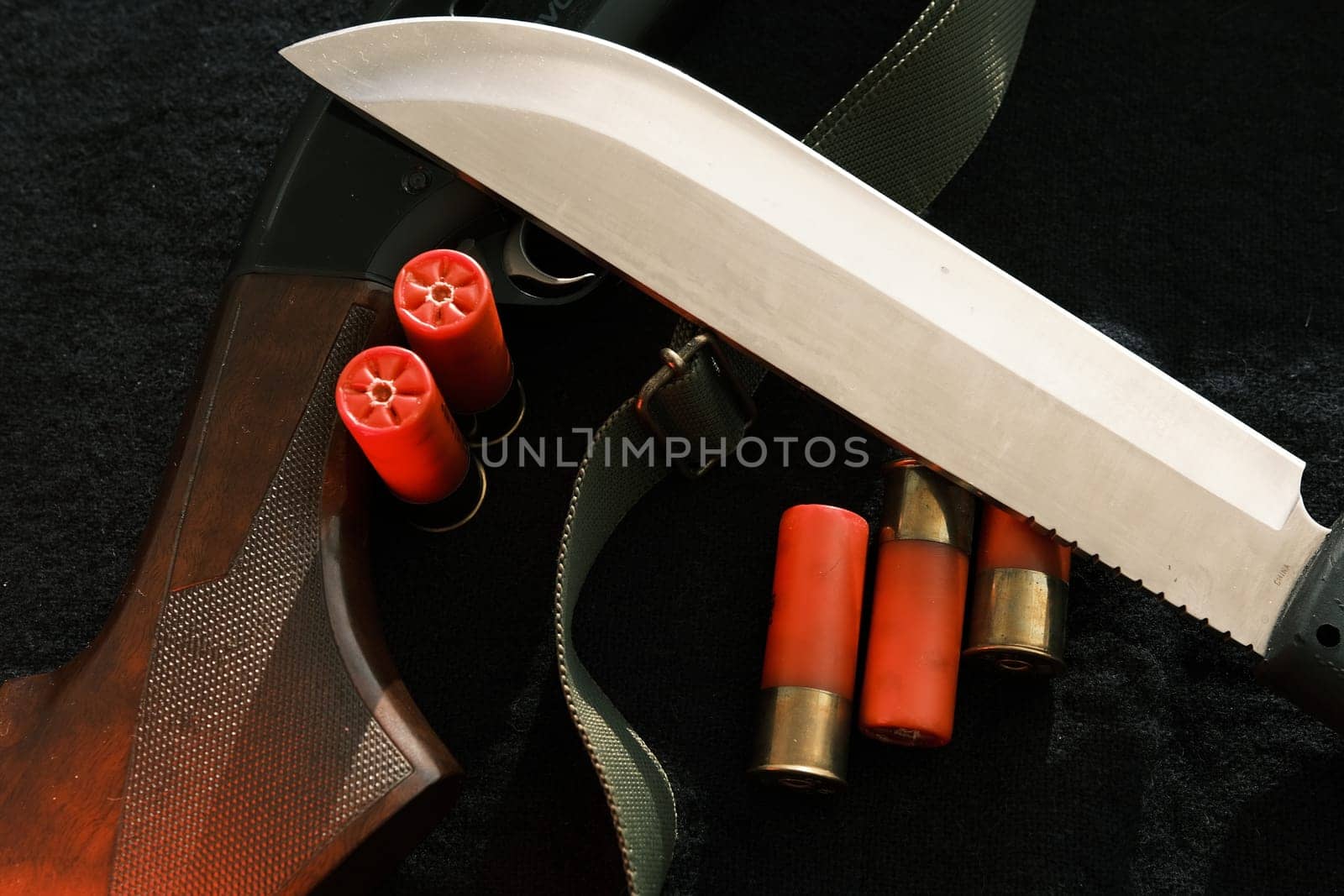 Weapon on black cloth: knife, rifle, shells,top view. Top view of knife, rifle shells