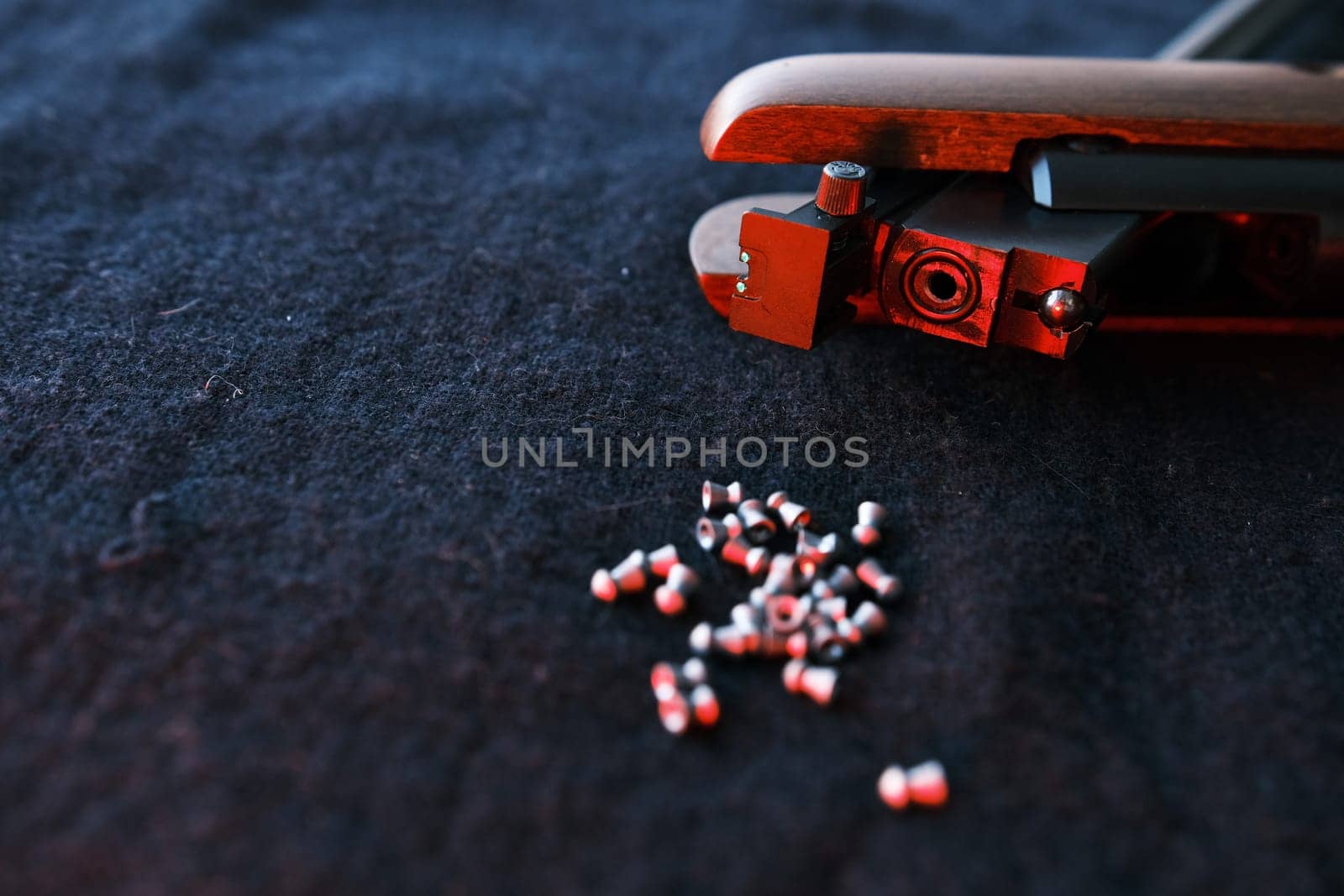 Rifle gun break in two with air pellets for hunting on cloth dark background with red light close up of rifle shutter hole.