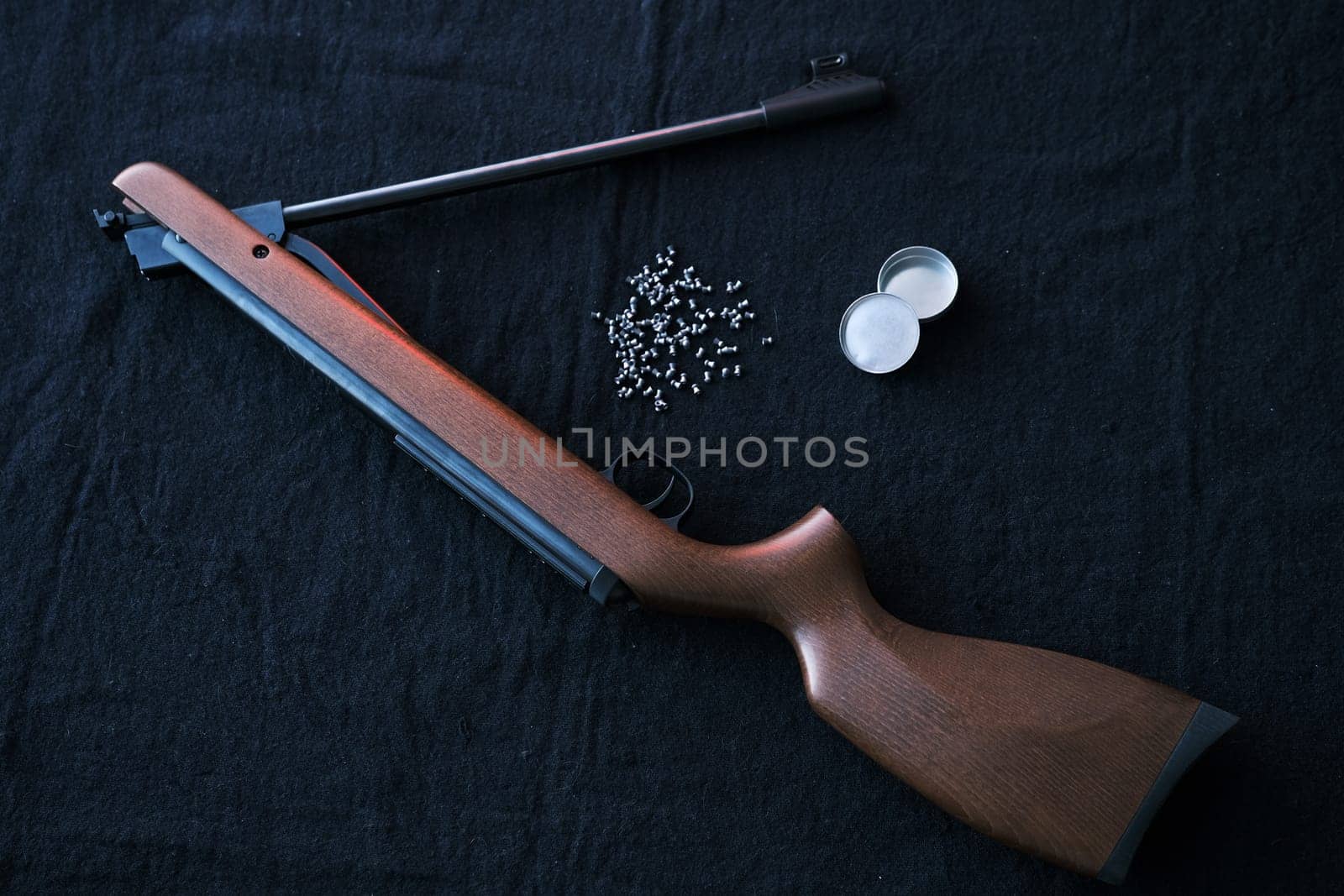 Rifle gun break in two with air pellets for hunting on cloth dark background.