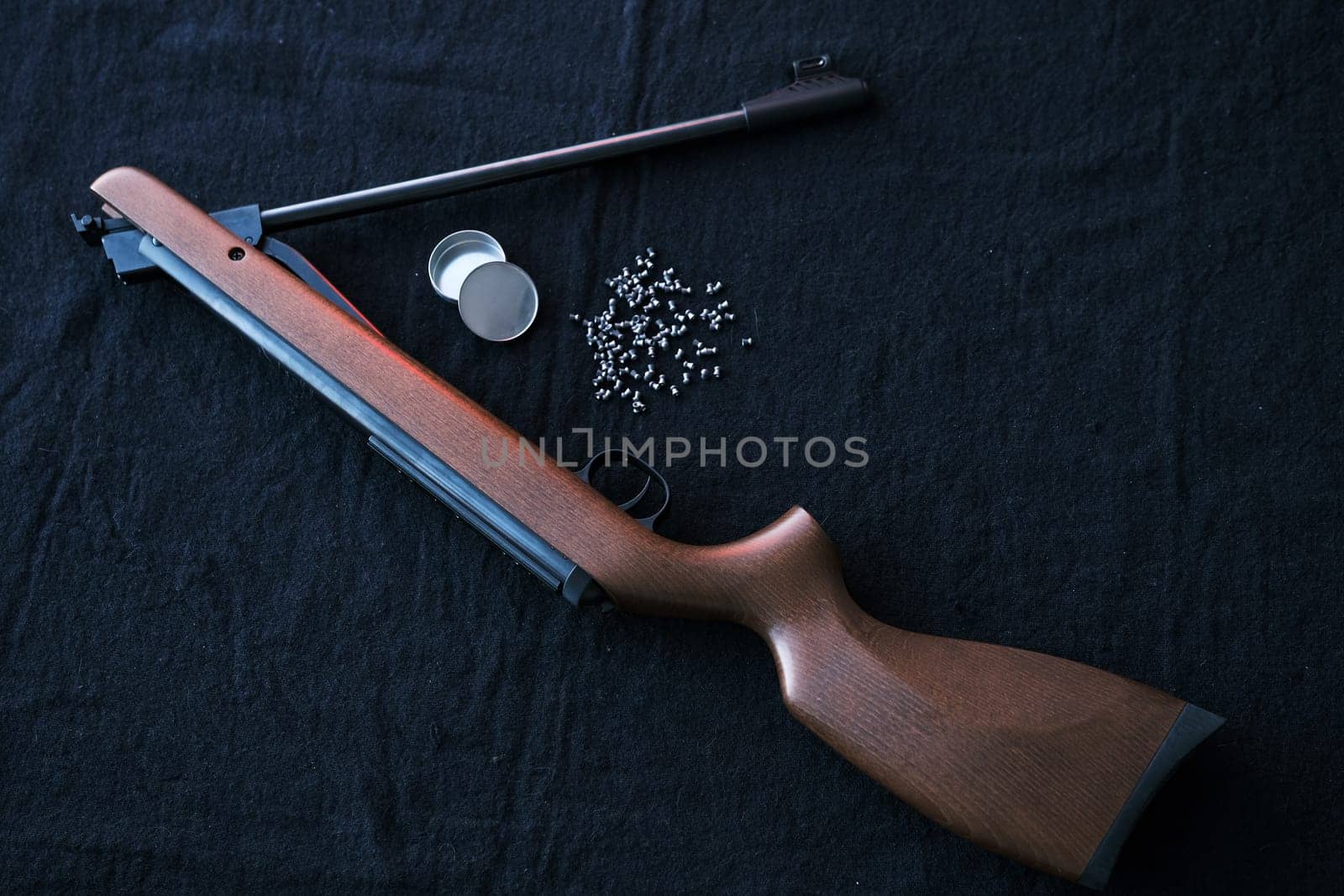Rifle gun break in two with air pellets for hunting on cloth dark background.