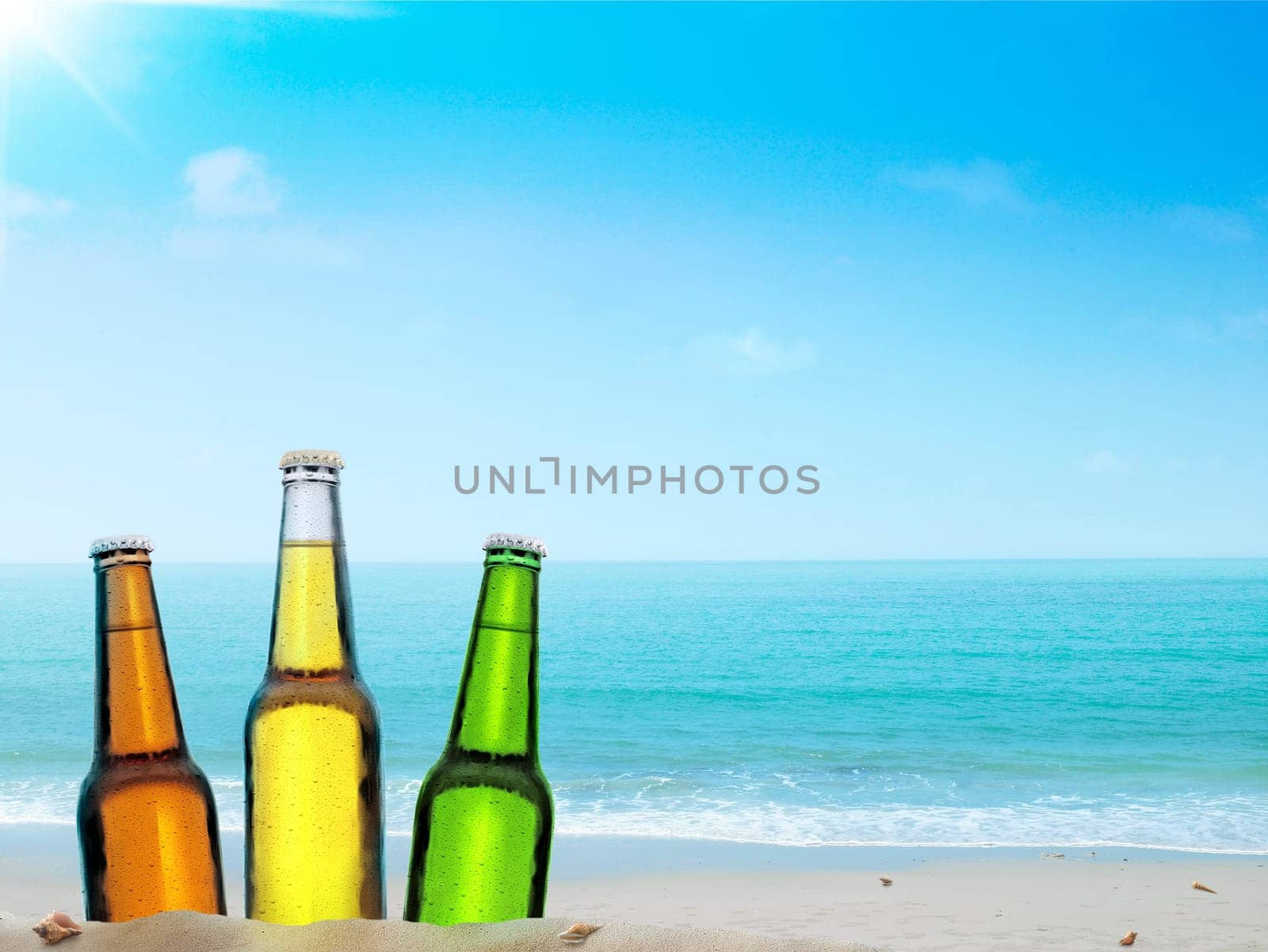 Bottle of beer on a sandy beach with clear sky