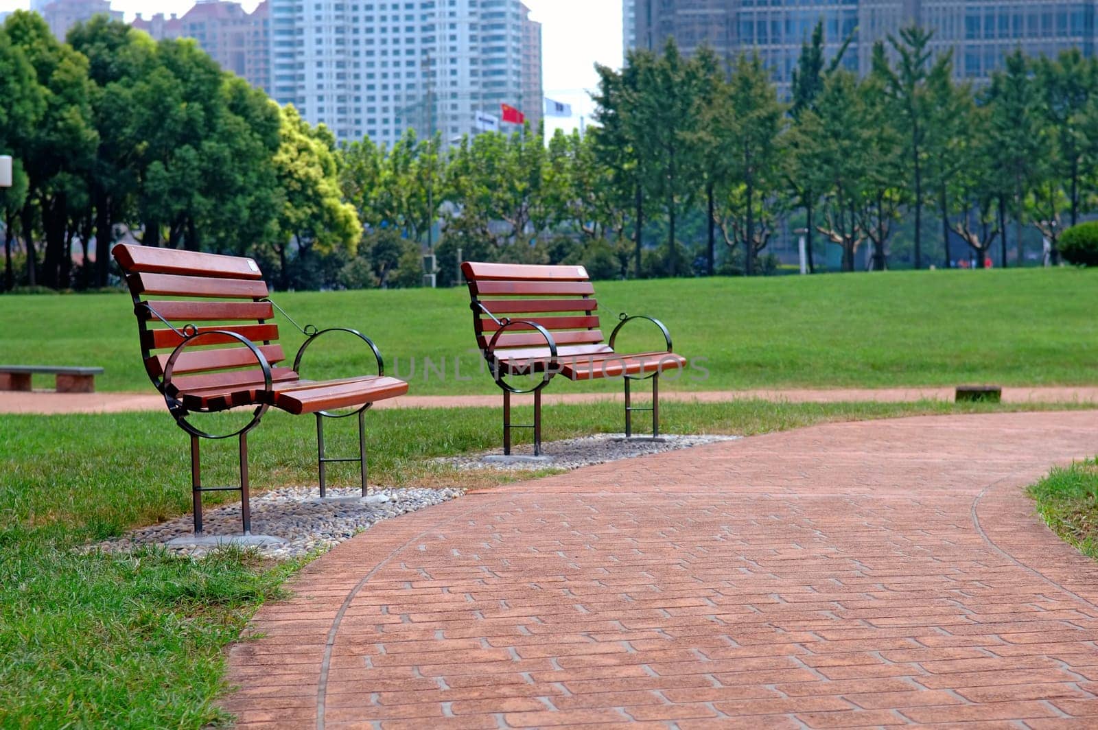 The walk way and bench of city park with building as background
