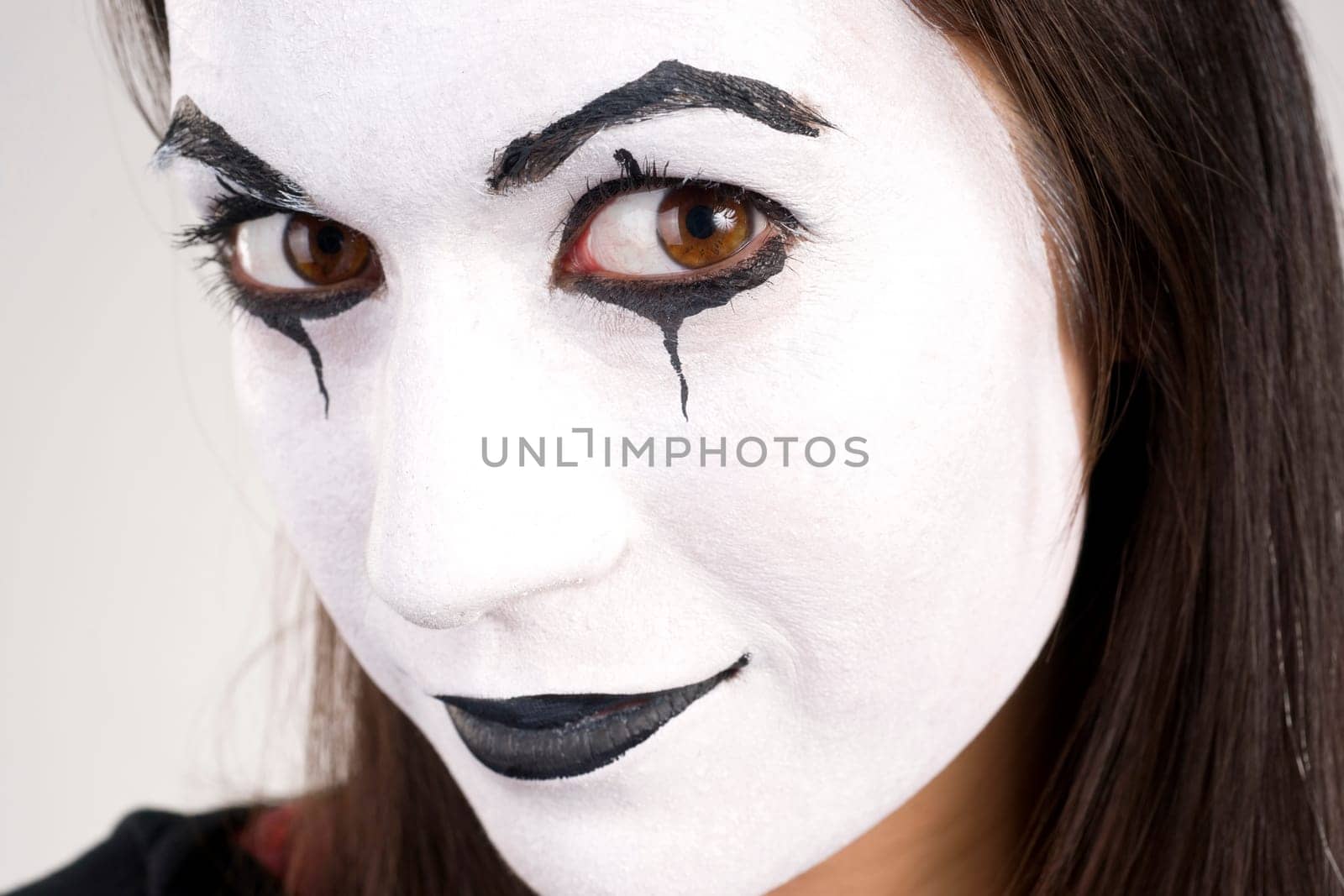 Woman made up in white face looks right into the camera