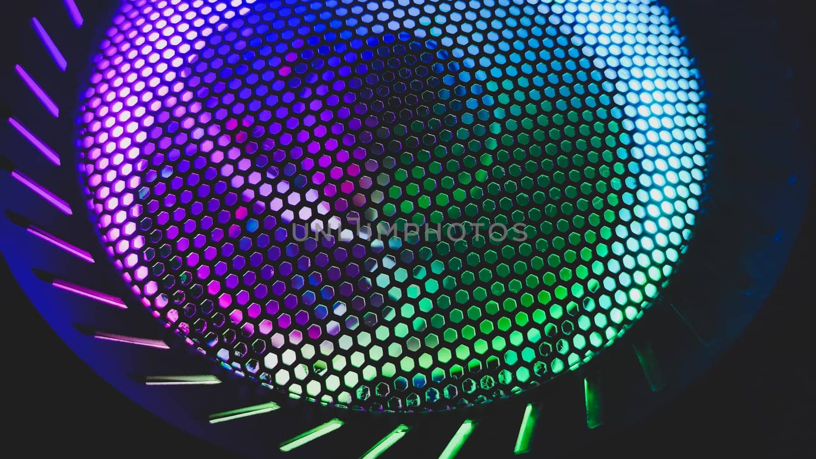Colorful led lights of computer fan shines through the protective grid. illumination glows in the dark. abstract futuristic background