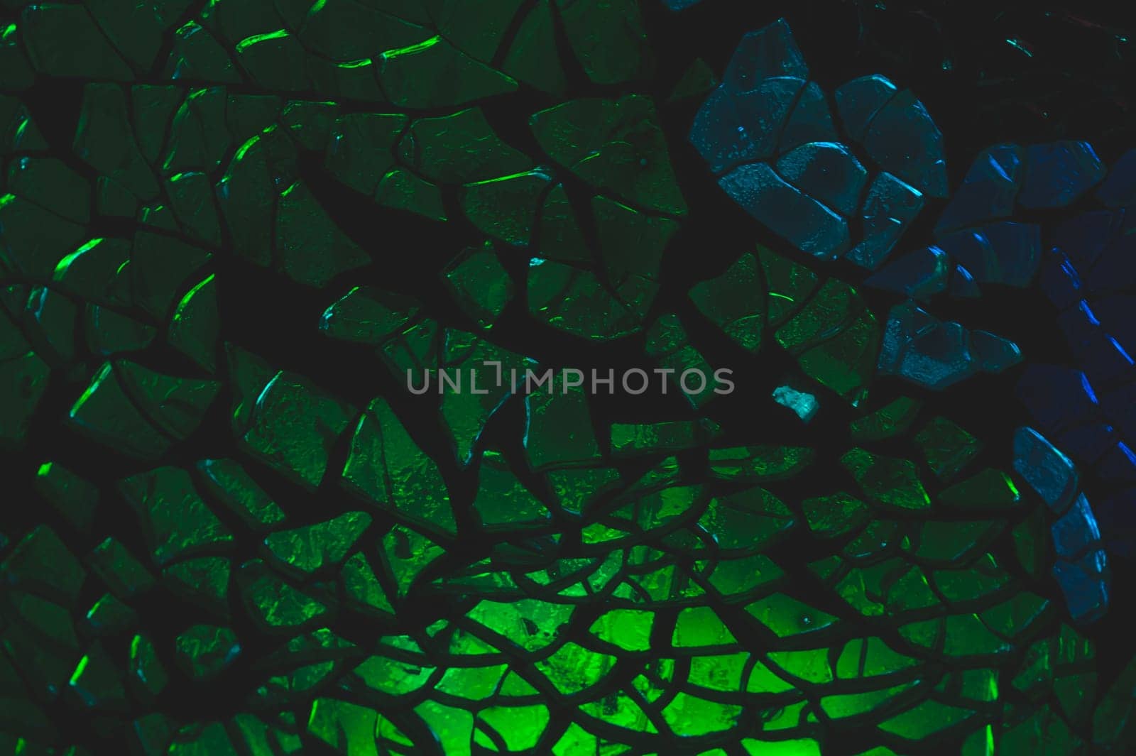 Shattered glass pattern in the dark. abstract cracked background. green and blue fragments