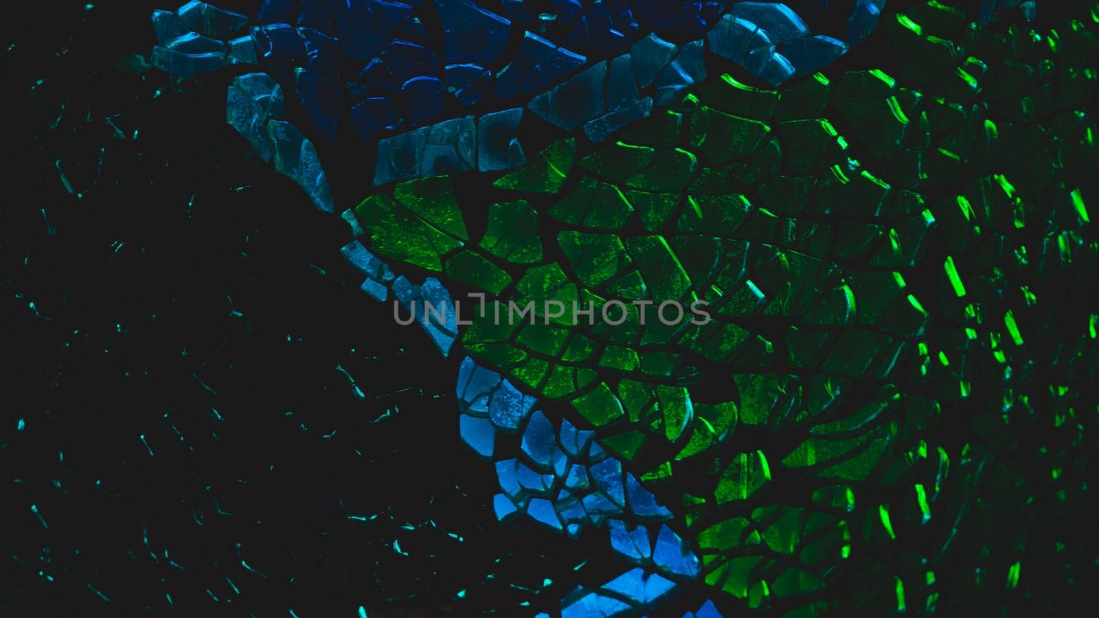 Shattered glass pattern in the dark. abstract cracked background. green and blue fragments