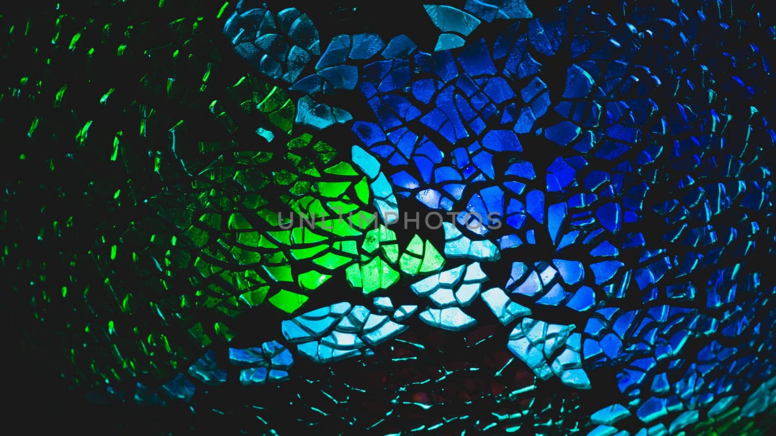 Shattered glass pattern in the dark. abstract cracked background. green and blue fragments