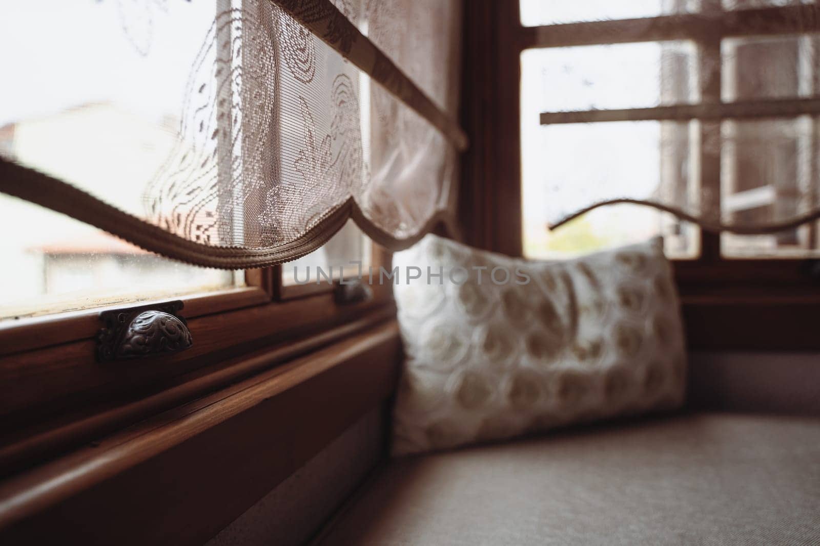 front view closeup of pillow with embroidery on divan in front of window