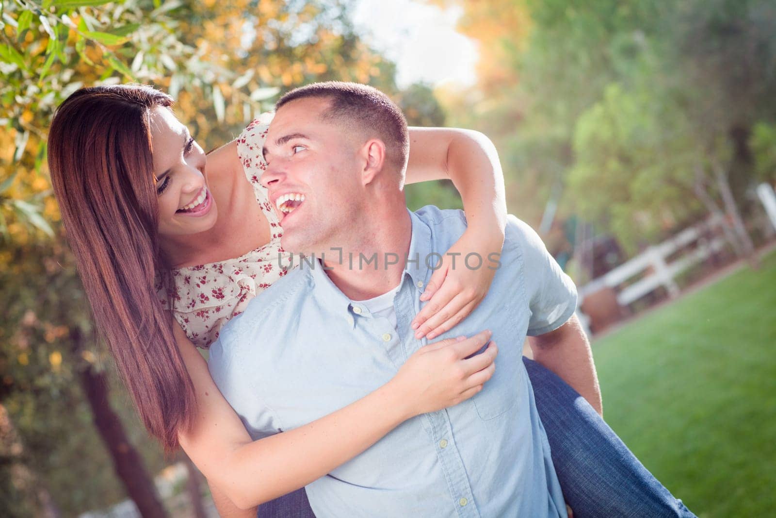Happy Romantic Caucasian Couple Piggyback Riding in the Park.