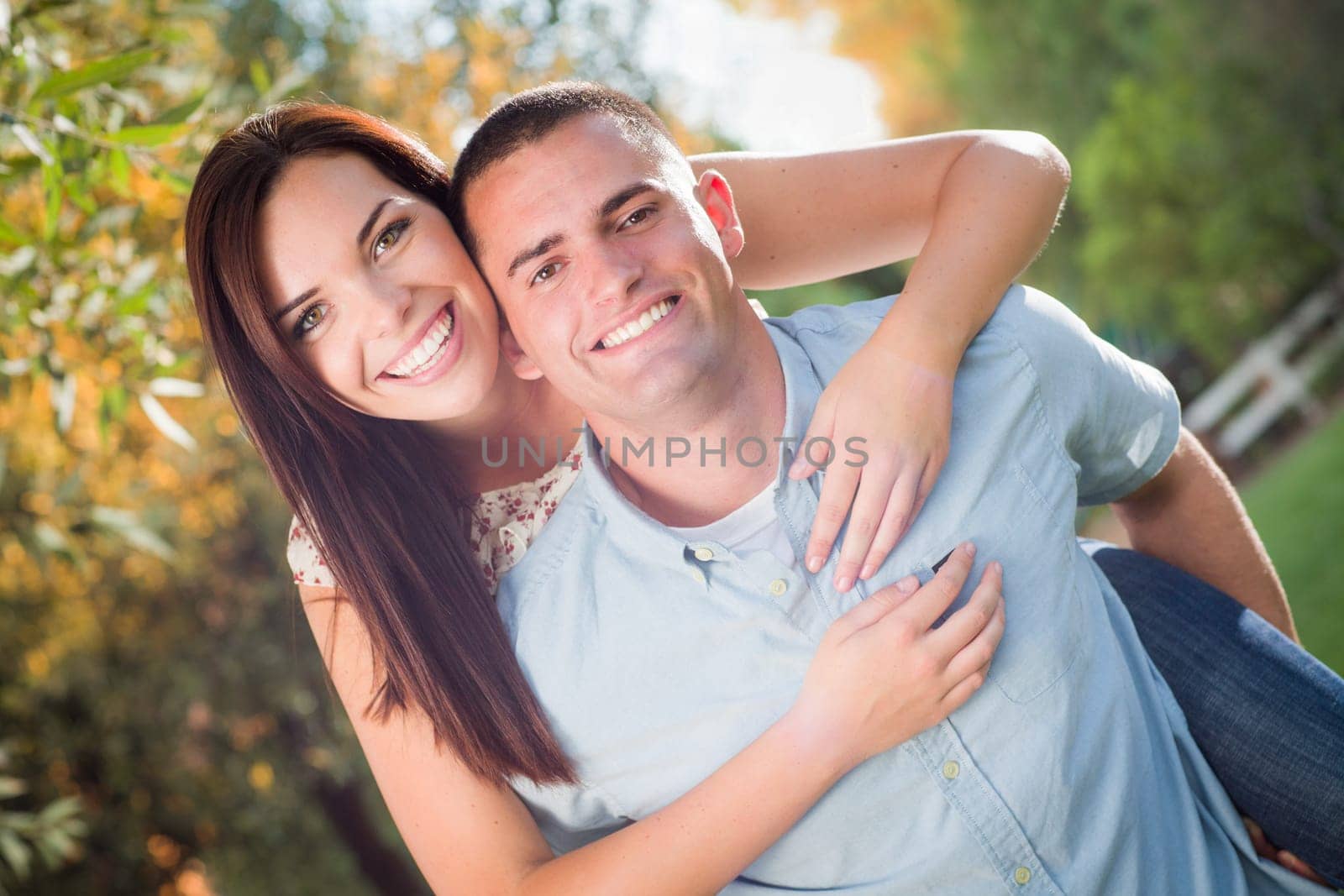 Happy Romantic Caucasian Couple Piggyback Riding in the Park.