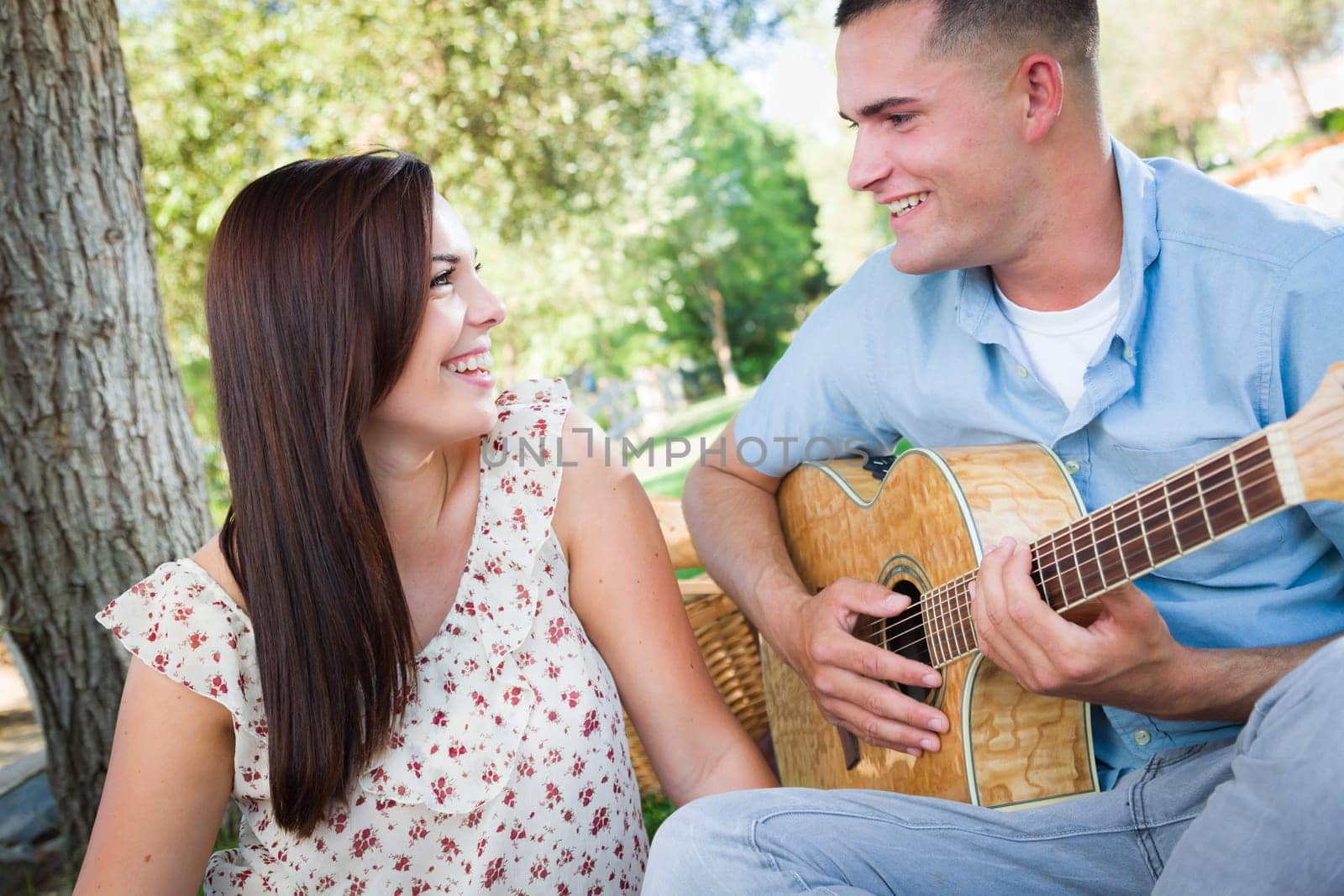 Young Adult Man Playing Guitar for His Girlfriend in the Park.