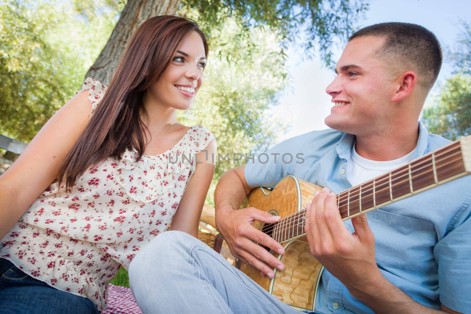 Young Adult Man Playing Guitar for His Girlfriend in the Park.