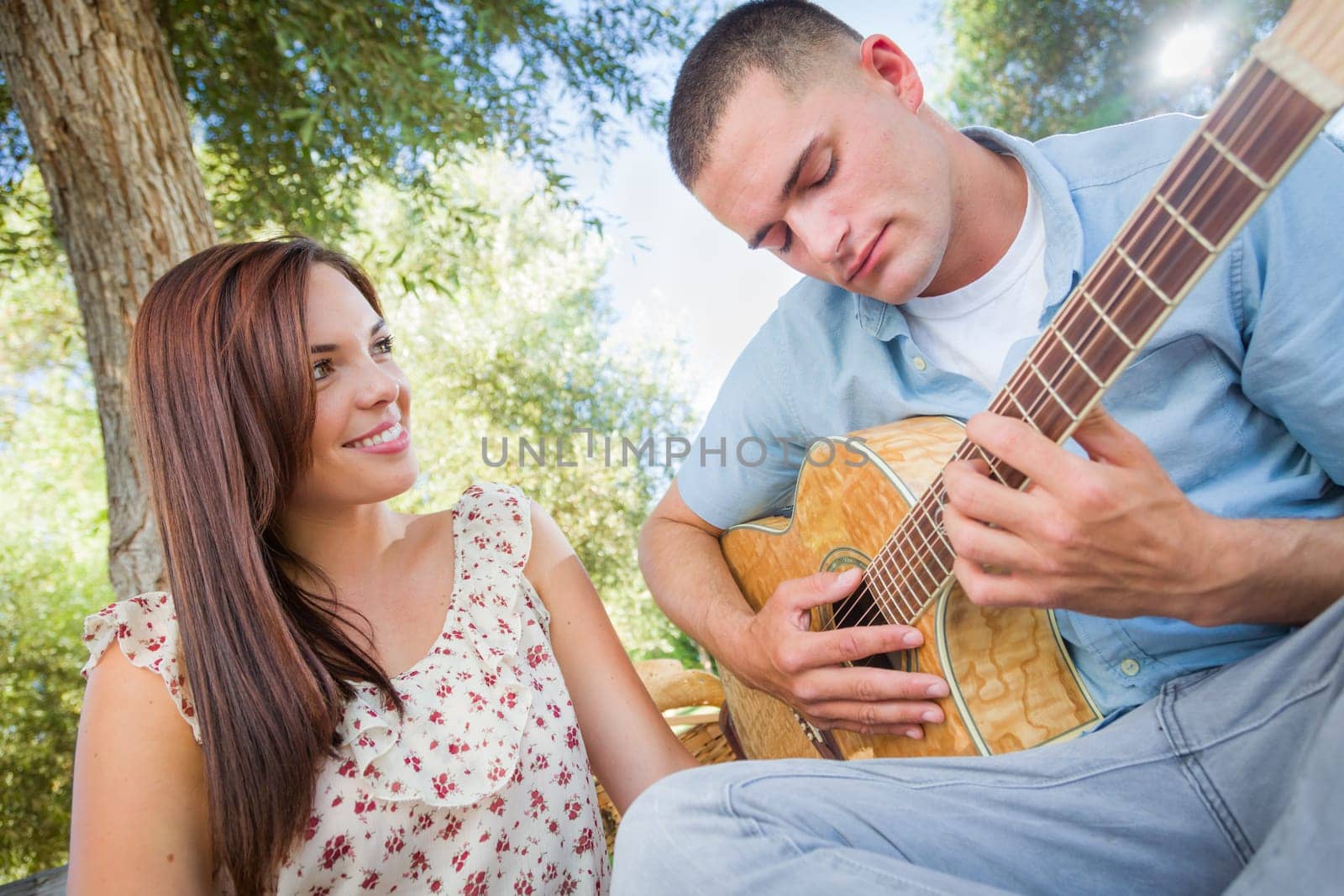 Young Adult Man Playing Guitar for His Girlfriend in the Park.