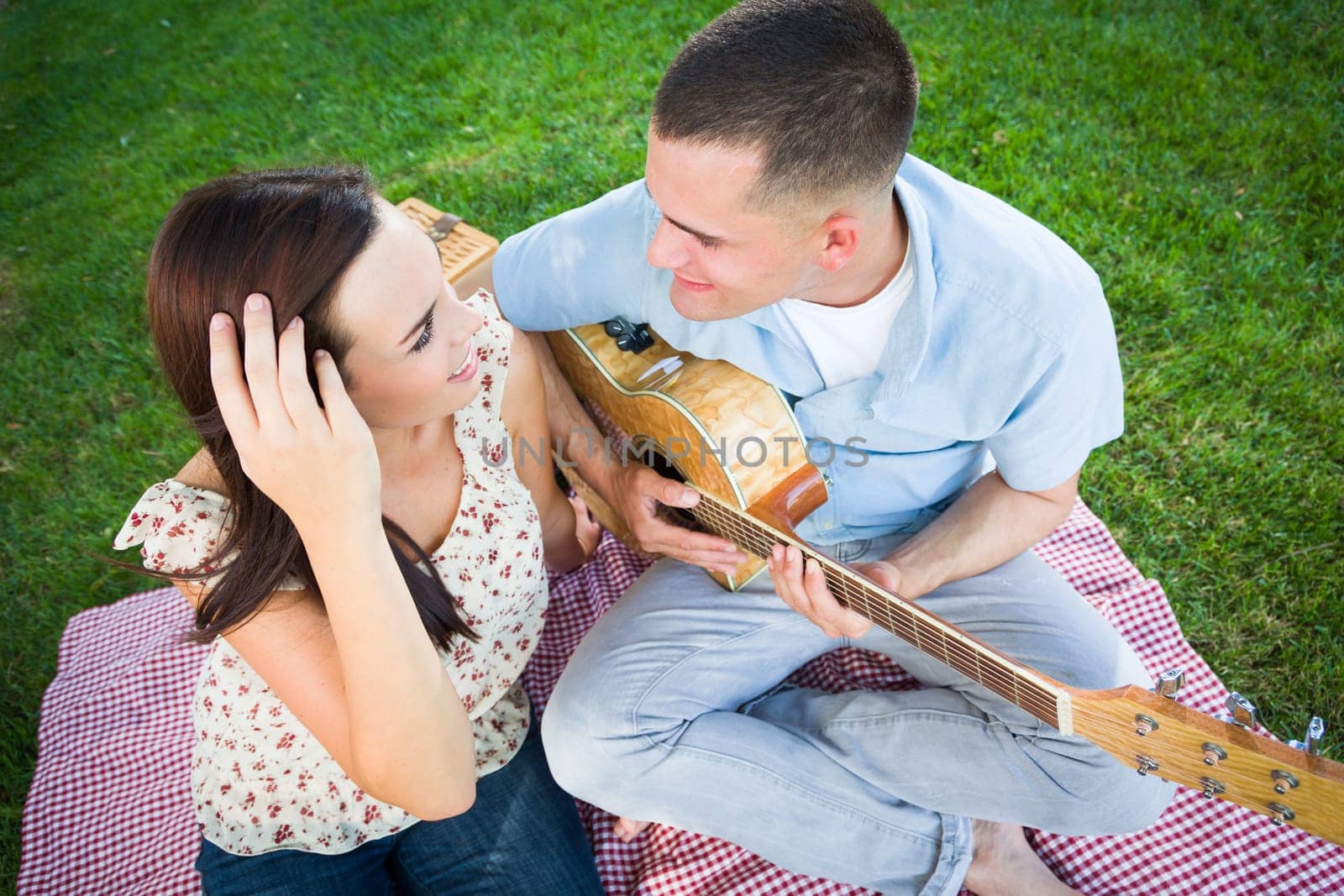 Young Adult Man Playing Guitar for His Girlfriend in the Park.