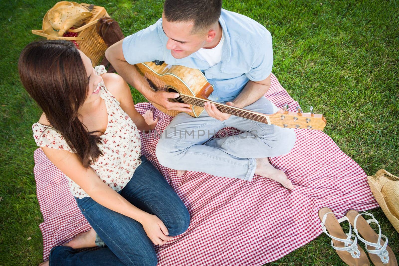 Young Adult Man Playing Guitar for His Girlfriend in the Park.
