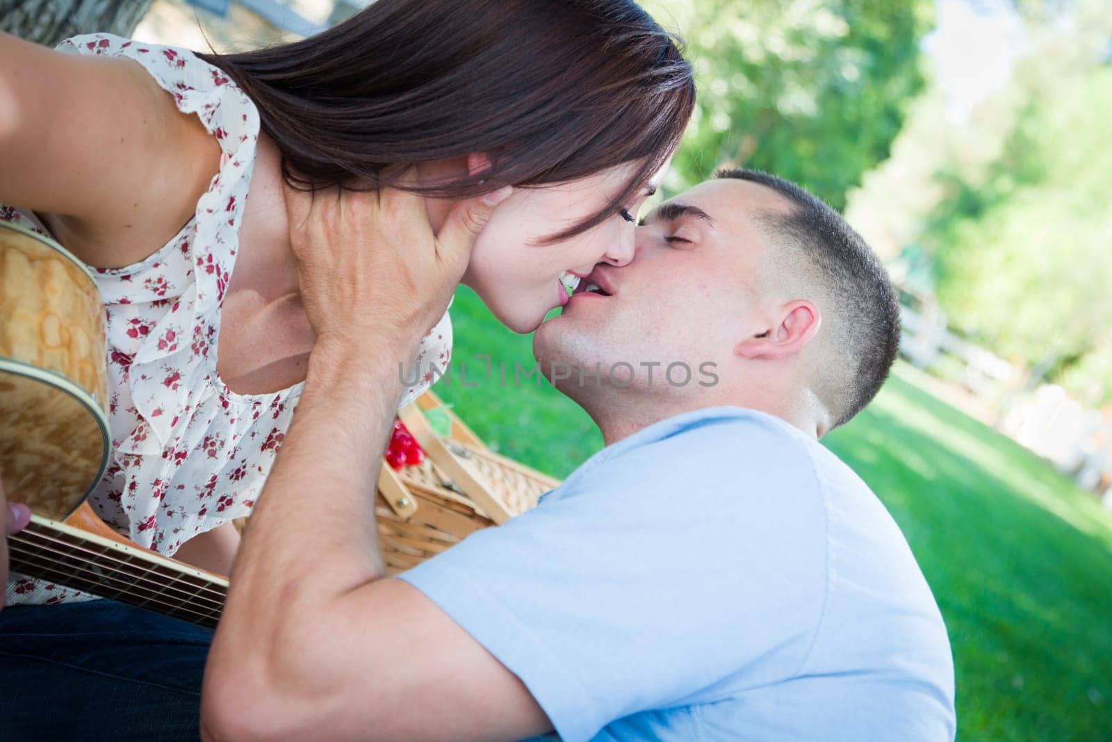 Young Adult Couple with Guitar Kissing in the Park.