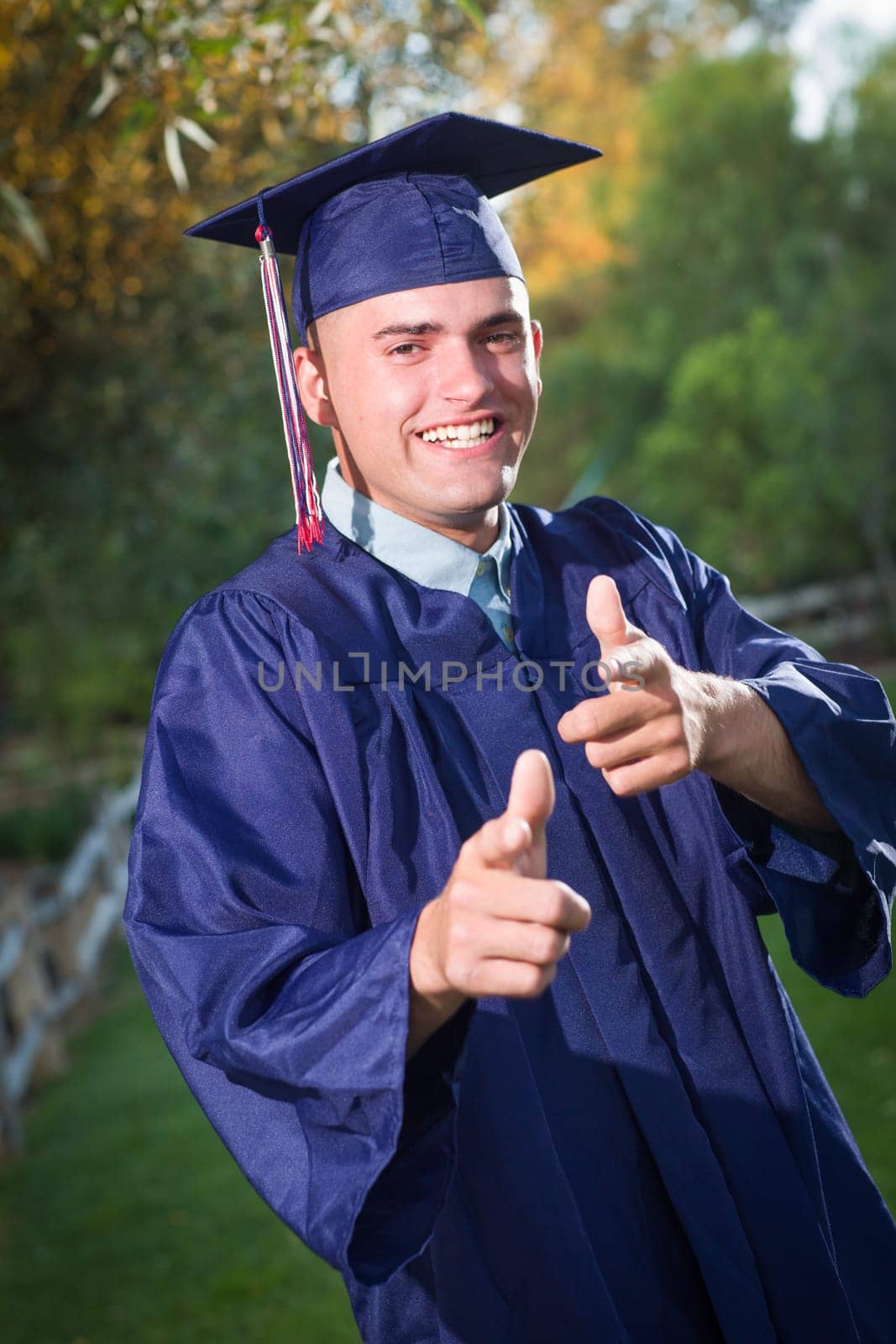 Happy Handsome Male Graduate in Cap and Gown Outside.