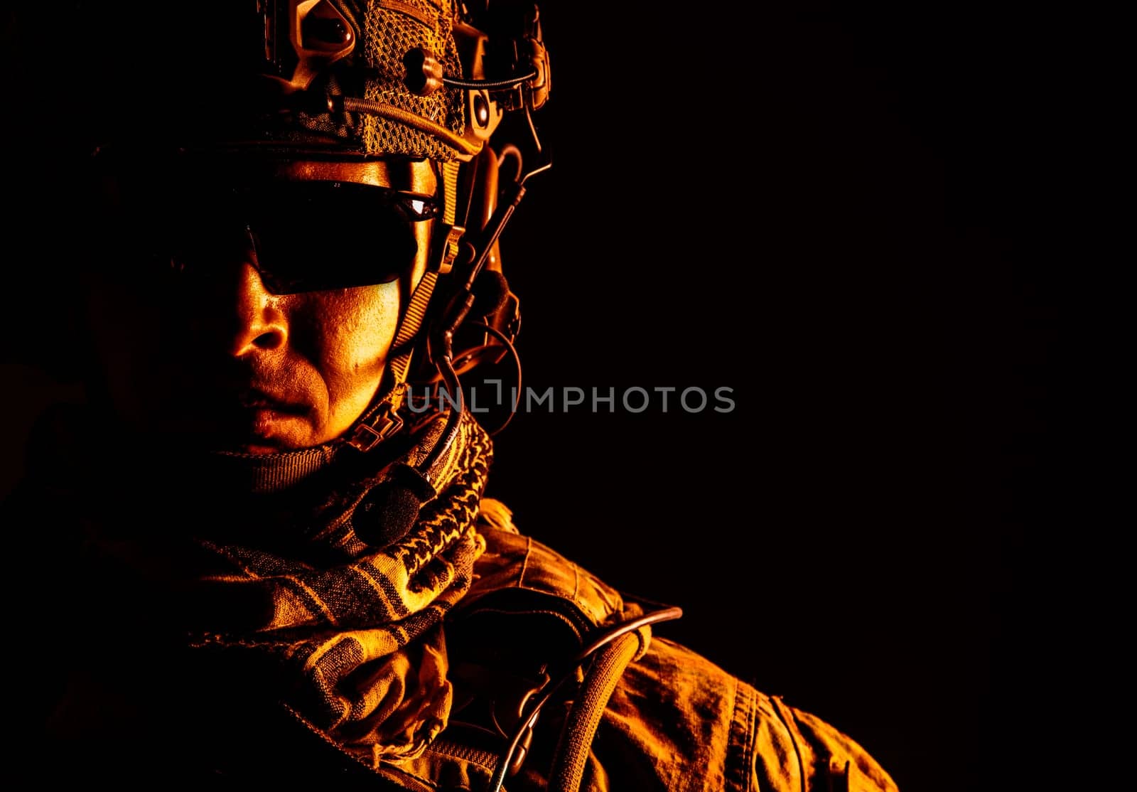 Elite member of US Army ranger in combat helmet and dark glasses. Studio shot, dark black background, looking at camera, dark contrast, toned and colorized