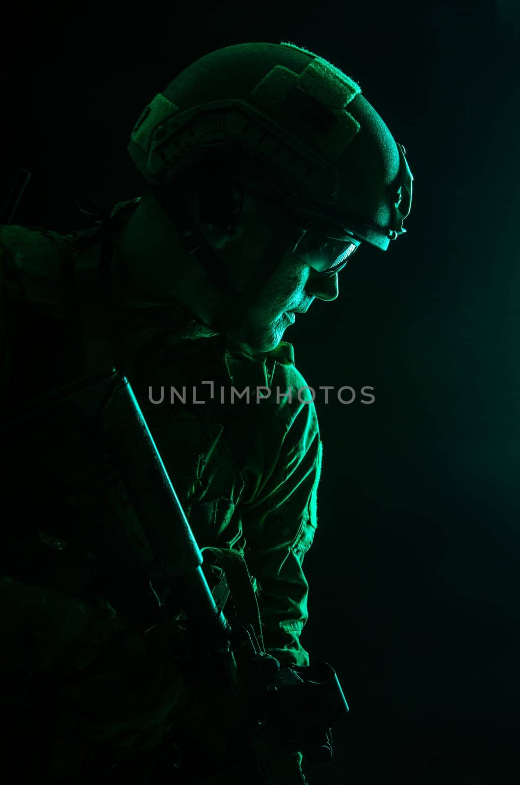 Studio contour backlight shot of special forces soldier in uniforms with weapons, portrait on black background
