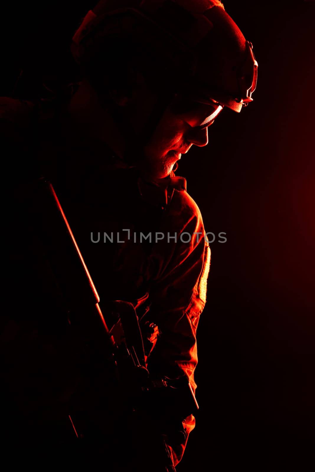 Studio contour backlight shot of special forces soldier in uniforms with weapons, portrait on black background