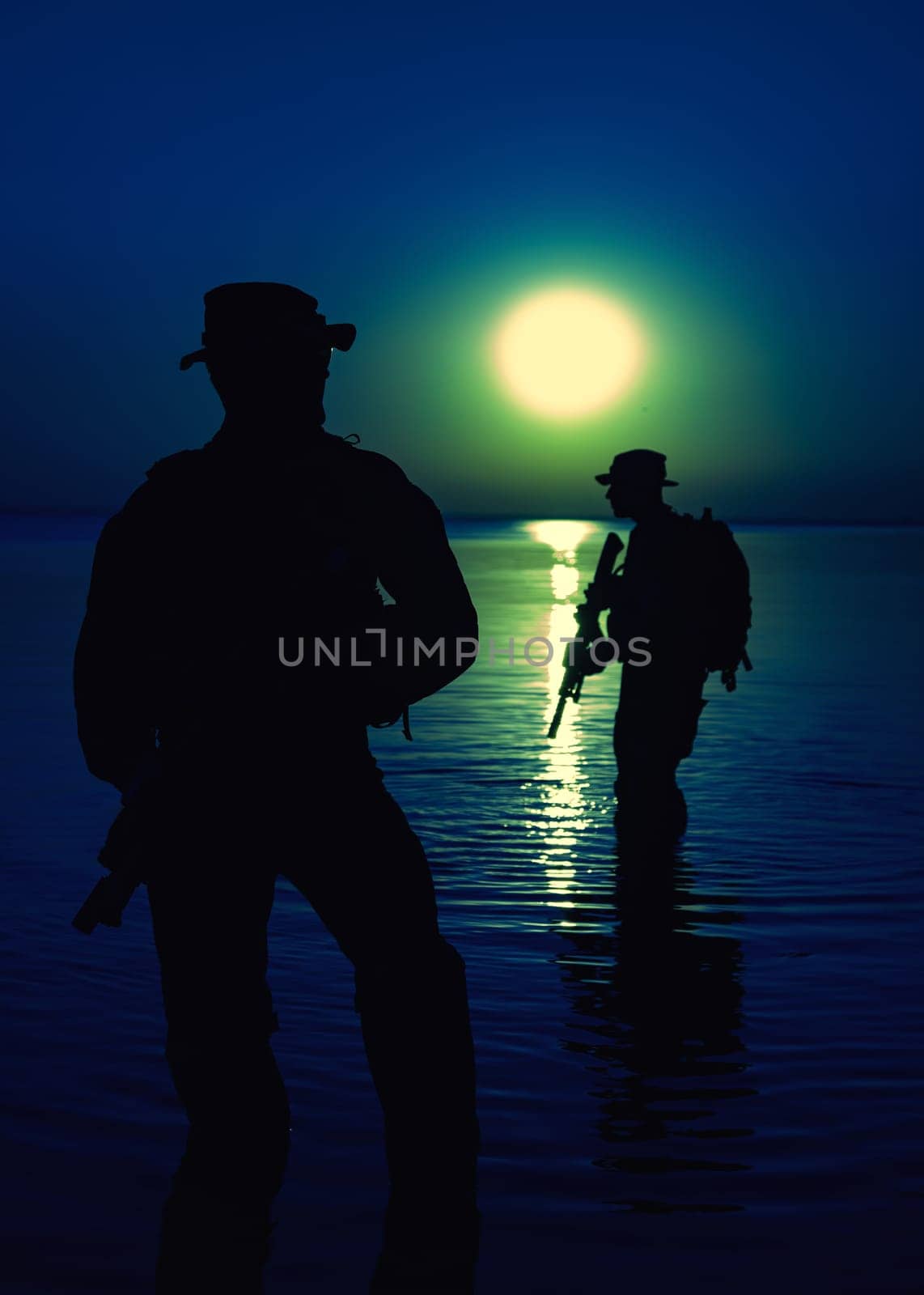 Army soldiers with rifles moon night silhouette in action during raid crossing river in the water, two militants with rifles at night