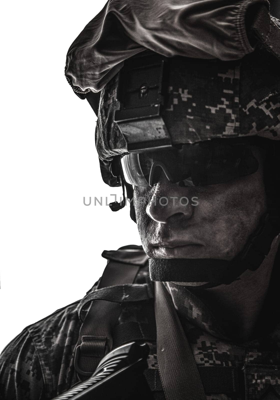 Shoulder portrait of modern army infantry soldier with dirty face in digital camouflage battle uniform, combat helmet, tactical sunglasses looking at camera desaturated, isolated on white background