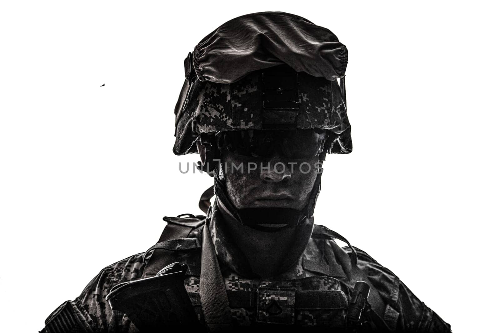 Shoulder portrait of modern army infantry soldier with dirty face in digital camouflage battle uniform, combat helmet, tactical sunglasses looking at camera desaturated, isolated on white background