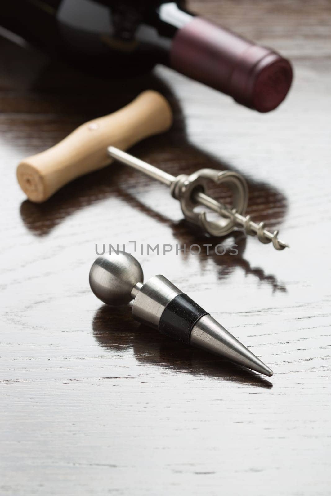 Abstract Wine Bottle, Corkscrew and Stopper Laying on a Reflective Wood Surface.