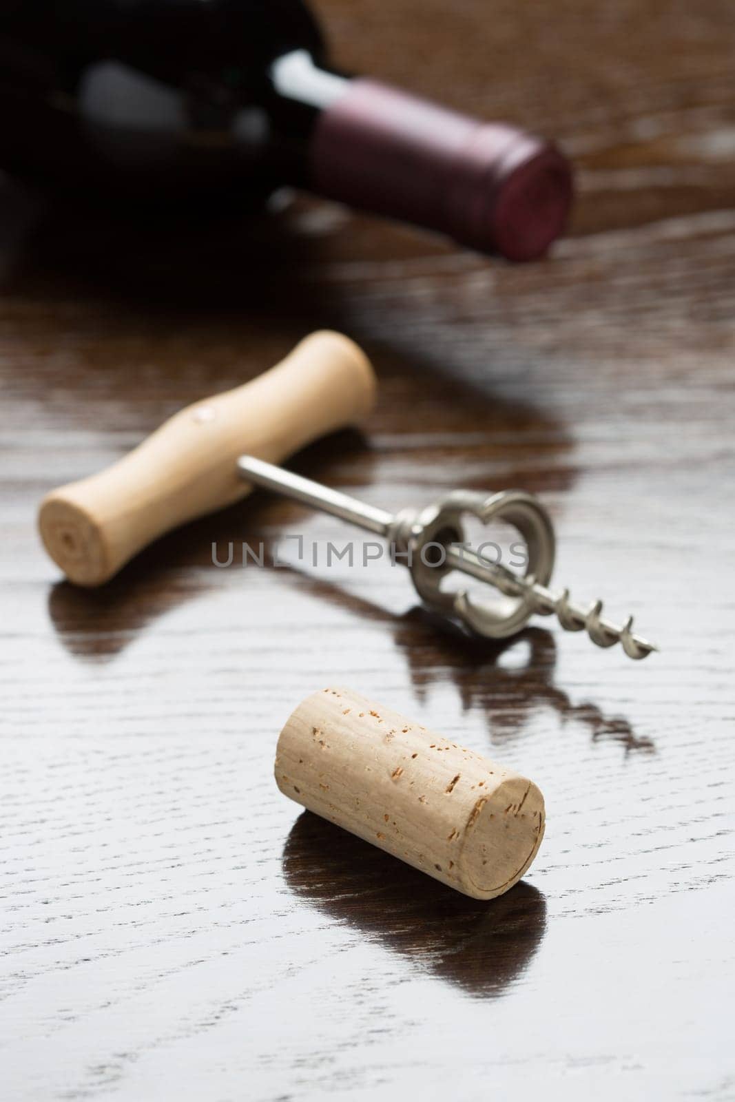 Abstract Wine Bottle, Cork and Corkscrew Laying on a Reflective Wood Surface.