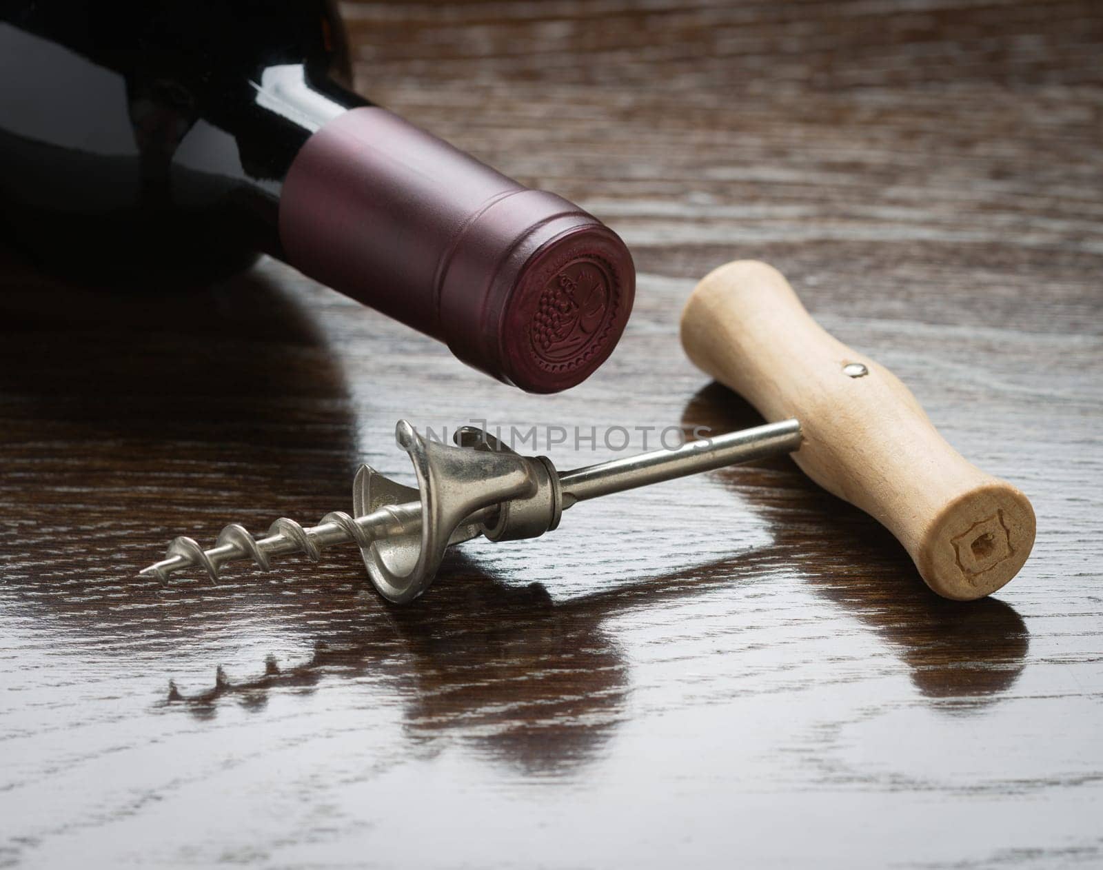 Abstract Wine Bottle and Corkscrew Laying on a Reflective Wood Surface.