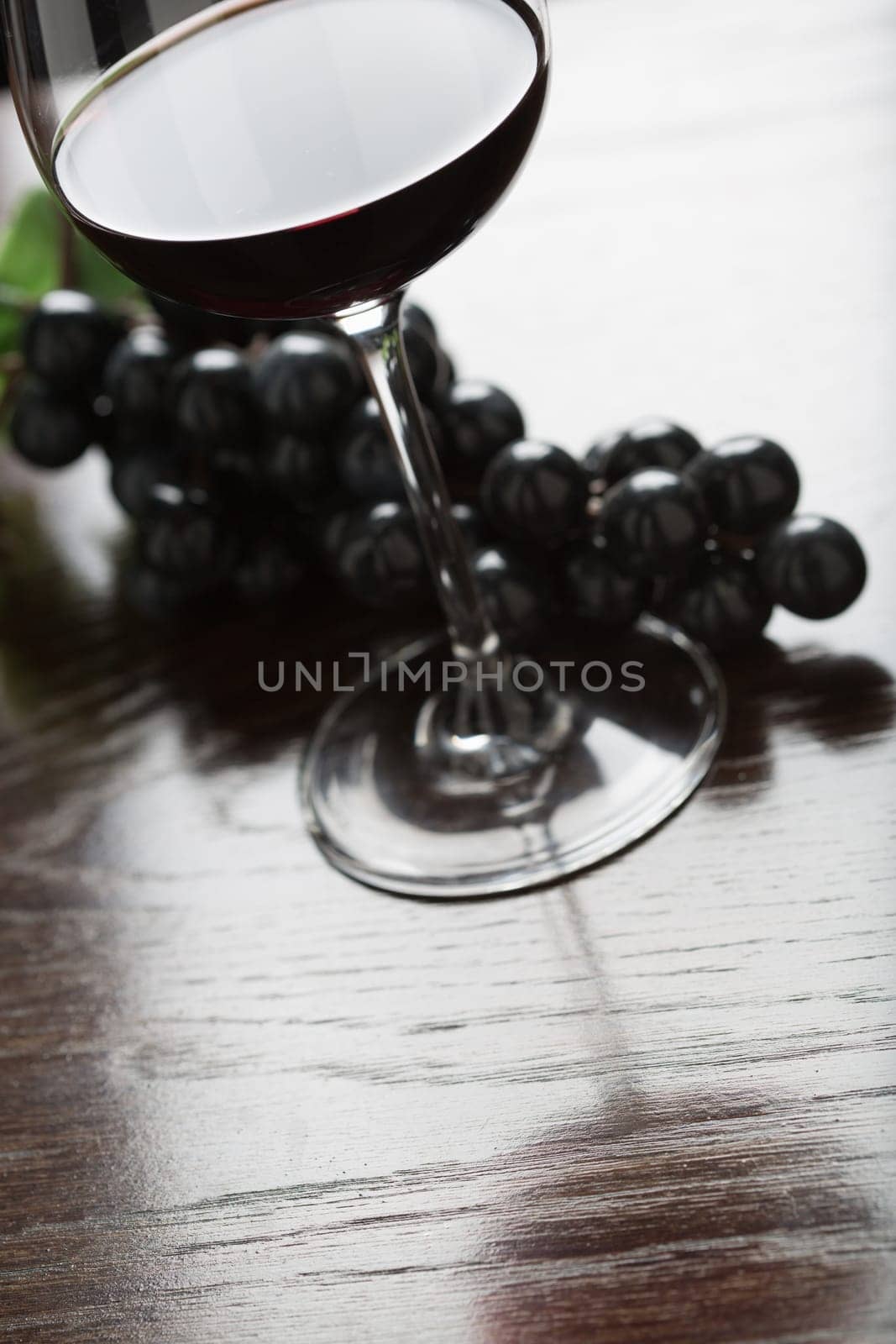Abstract Wine Glass and Grapes on a Reflective Wood Surface.
