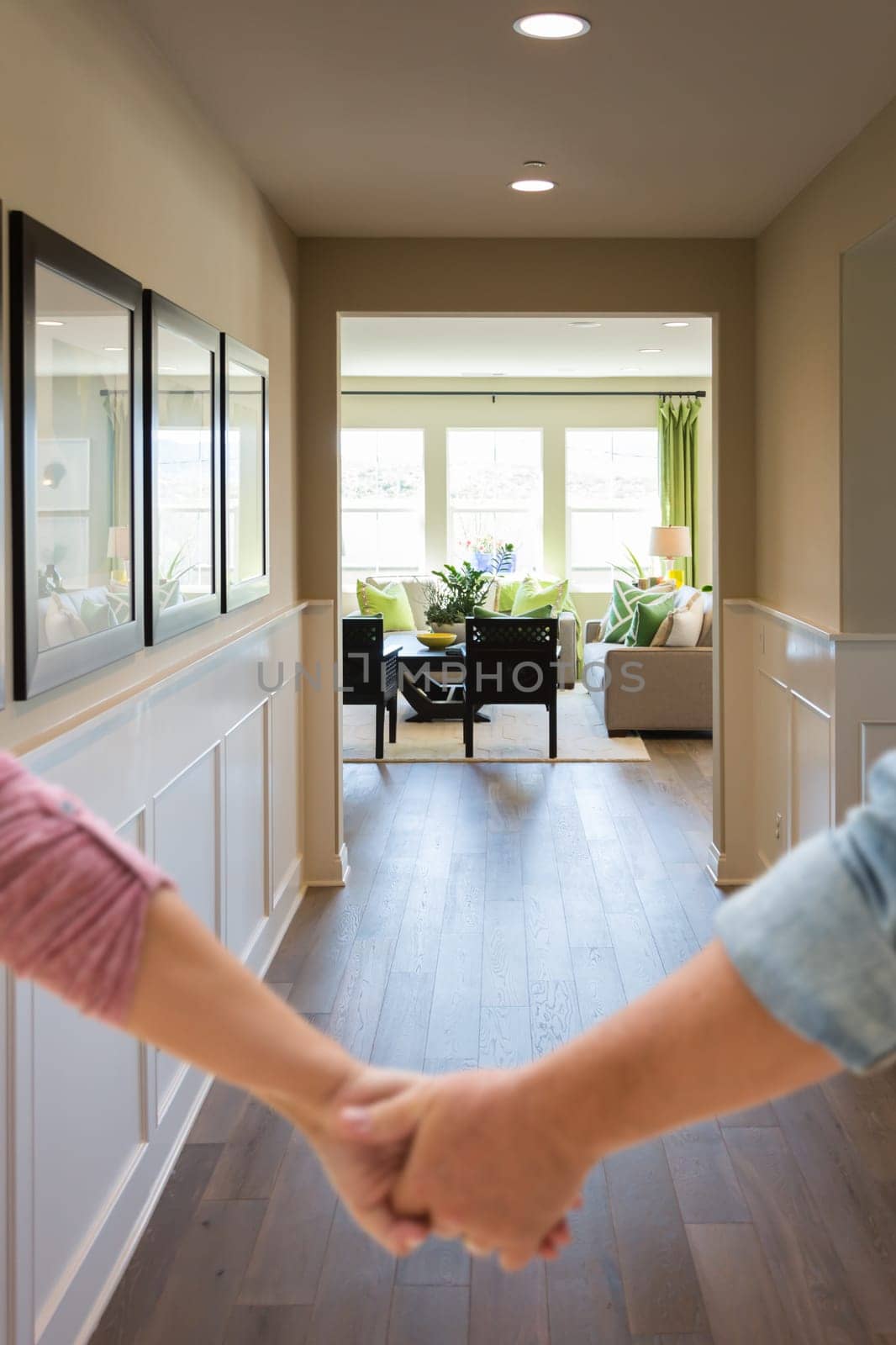 Couple Holding Hands Walking Through Hallway of New House.