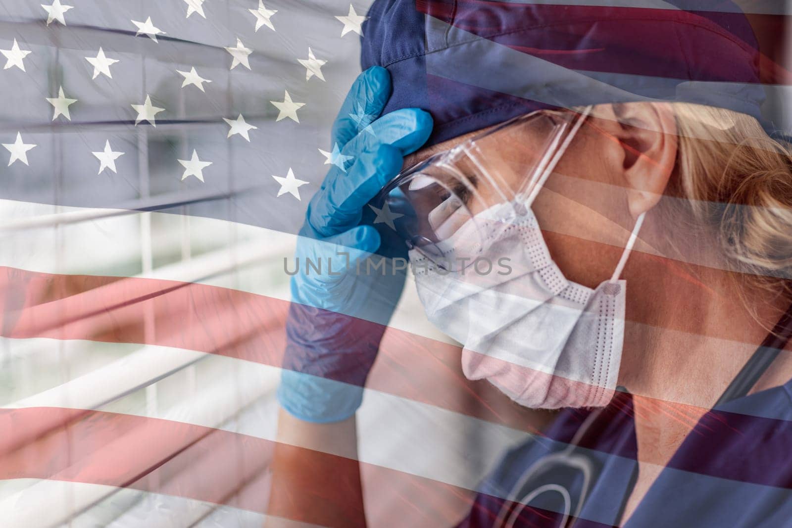 Stressed Female Doctor or Nurse On Break At Window Wearing Medical Face Mask and Goggles With Ghosted American Flag.