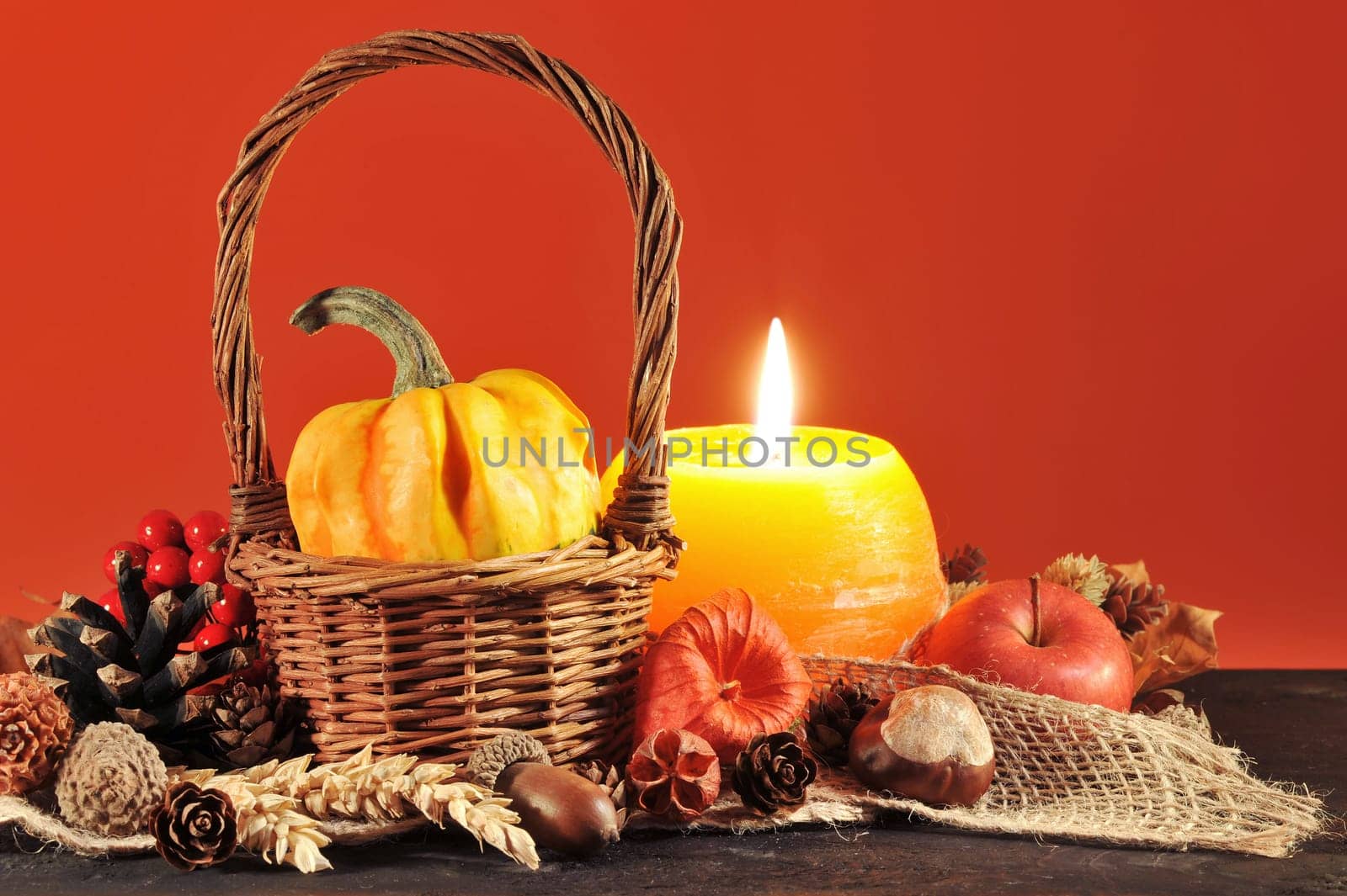 small pumpkin in a basket on old weathered wooden boards by candlelight