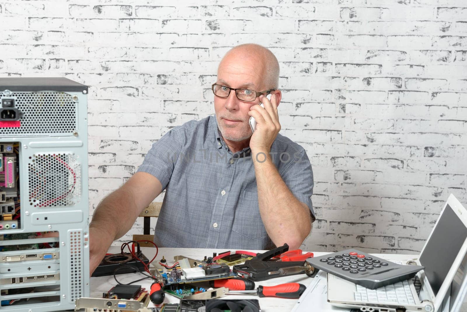 a technician repairing a computer and phone to the customer