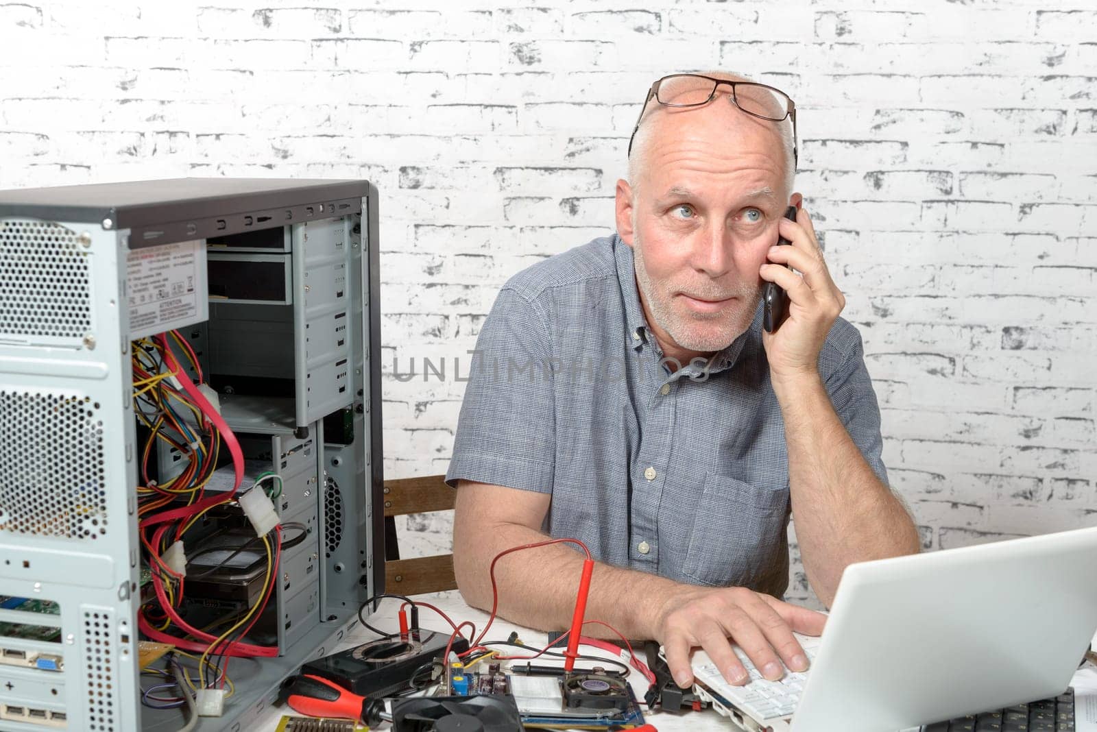 a technician repairing a computer and phone to the customer