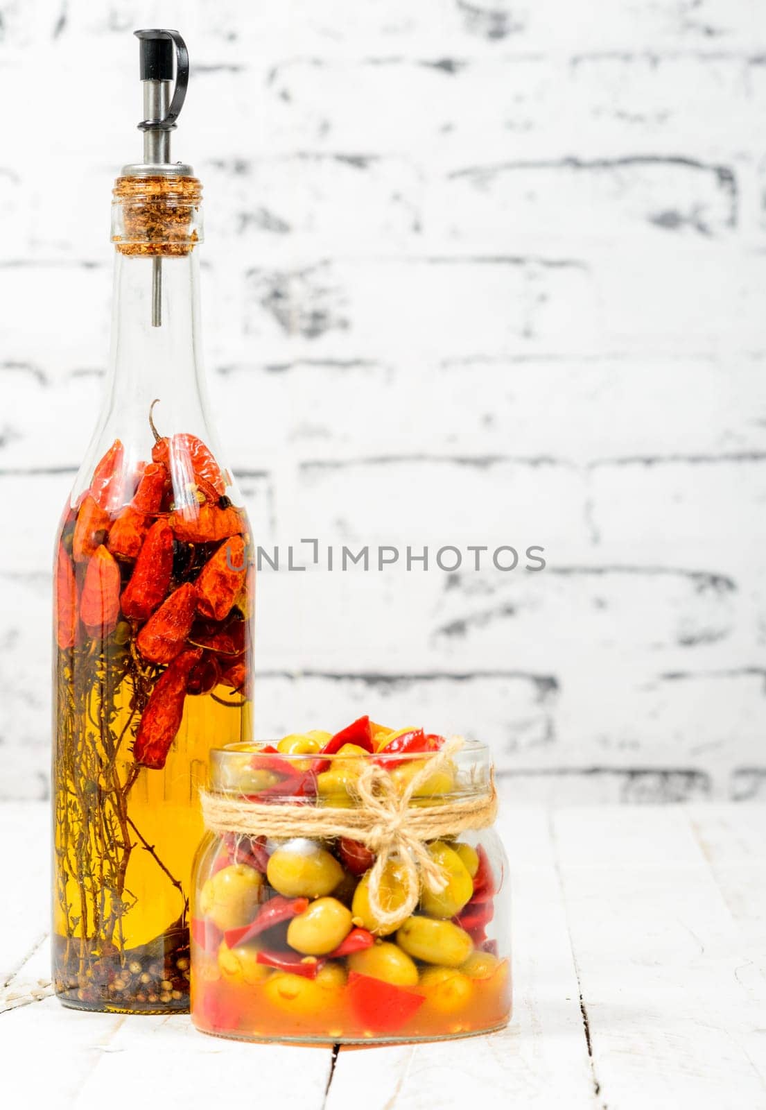 glass jar with olives and peppers on old white table