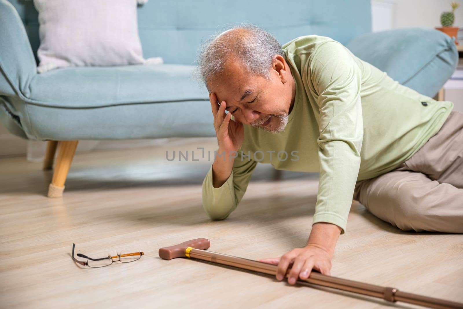 Sick senior old man falling down lying on the ground because stumbled at home alone with wooden walking stick in living room, elderly man grandfather having accident while walk with cane walker