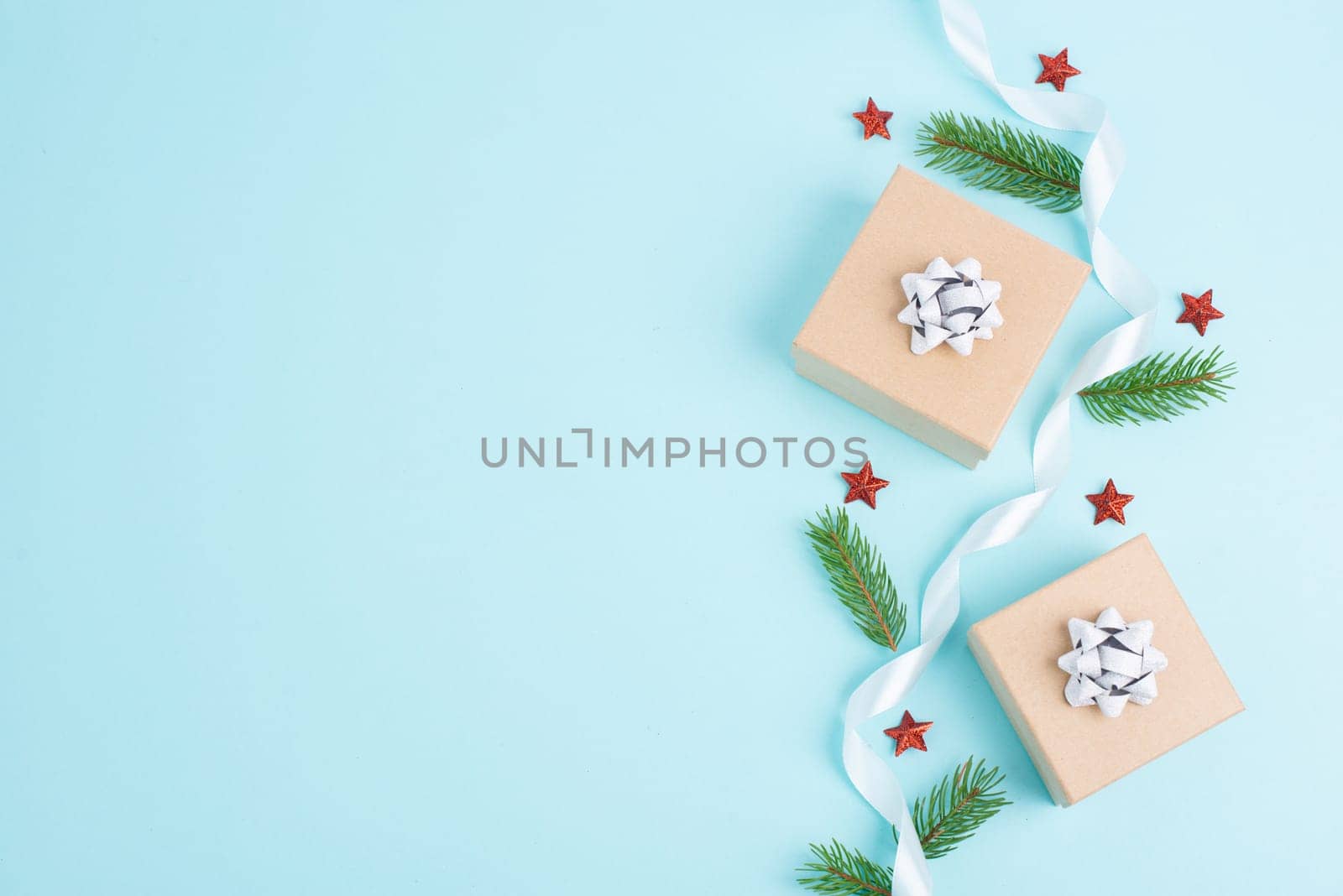 Christmas holiday greeting card with little gift box, stars, ribbon and fir branches, blue background