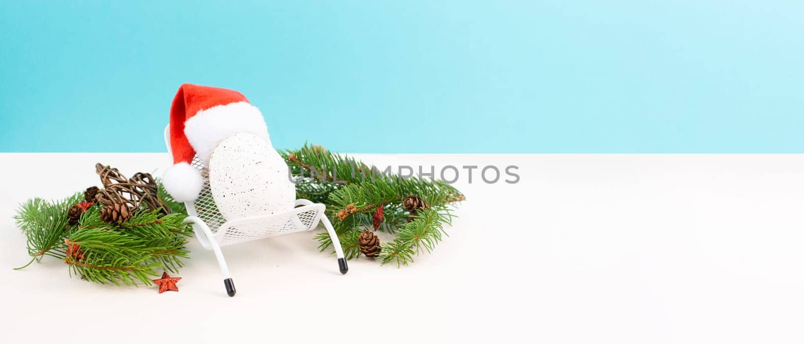 Santa Claus with a red hat sitting in a lounge chair, holiday by the sea, taking a vacation, christmas decoration with fir, cones and stars