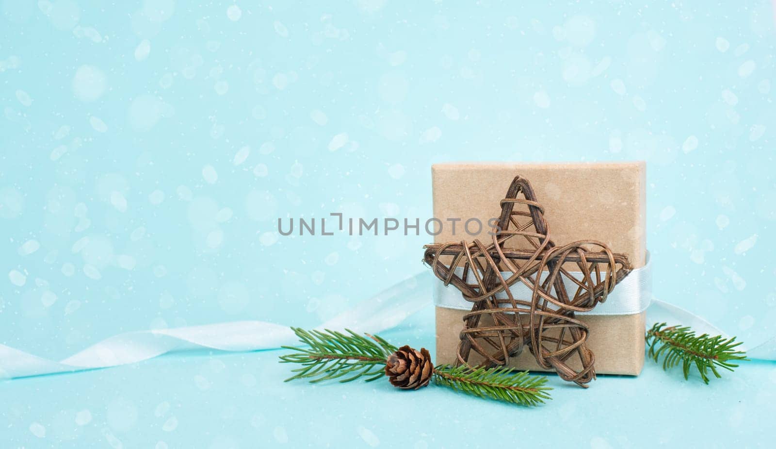 Christmas holiday greeting card with little gift box, pine cones and fir branches, blue background with snow