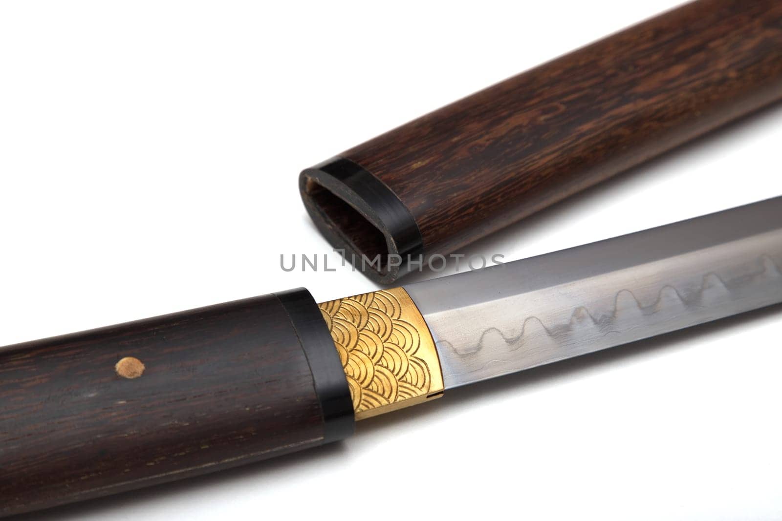 Close-up of a Japanese sword with a handle and a wooden sheath, called Shirasaya, and at the base of the blade, a brass sheath, called habaki, is used to tighten the sword. Soft focus.on white BG.