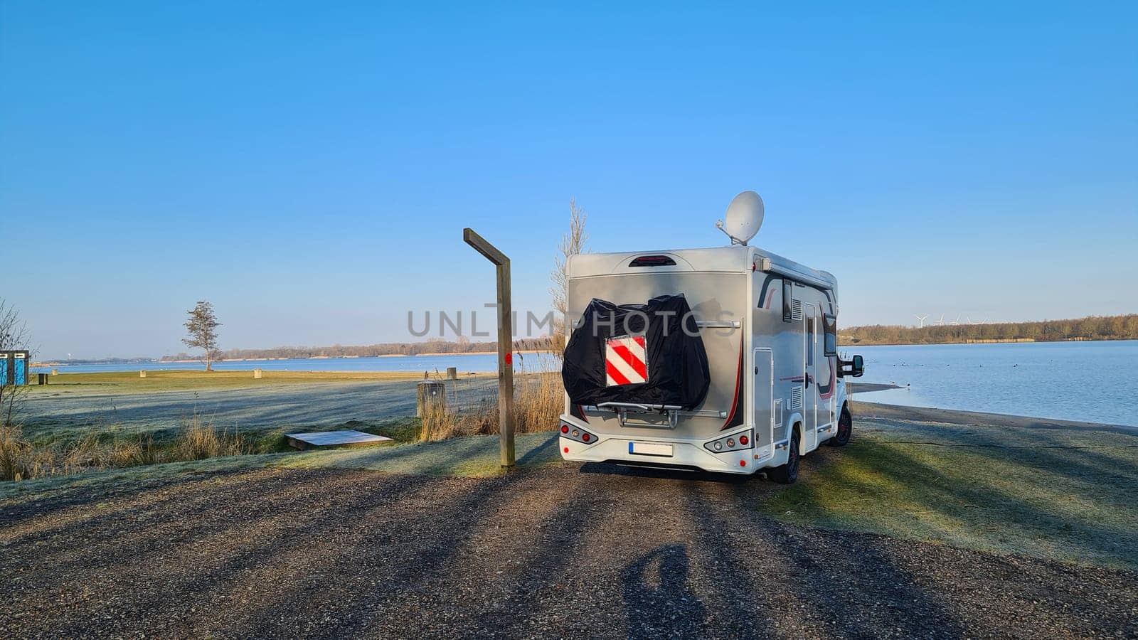 Autumn RV camping. Modern camper van in the late sunny autumn afternoon. Picturesque RV Park.