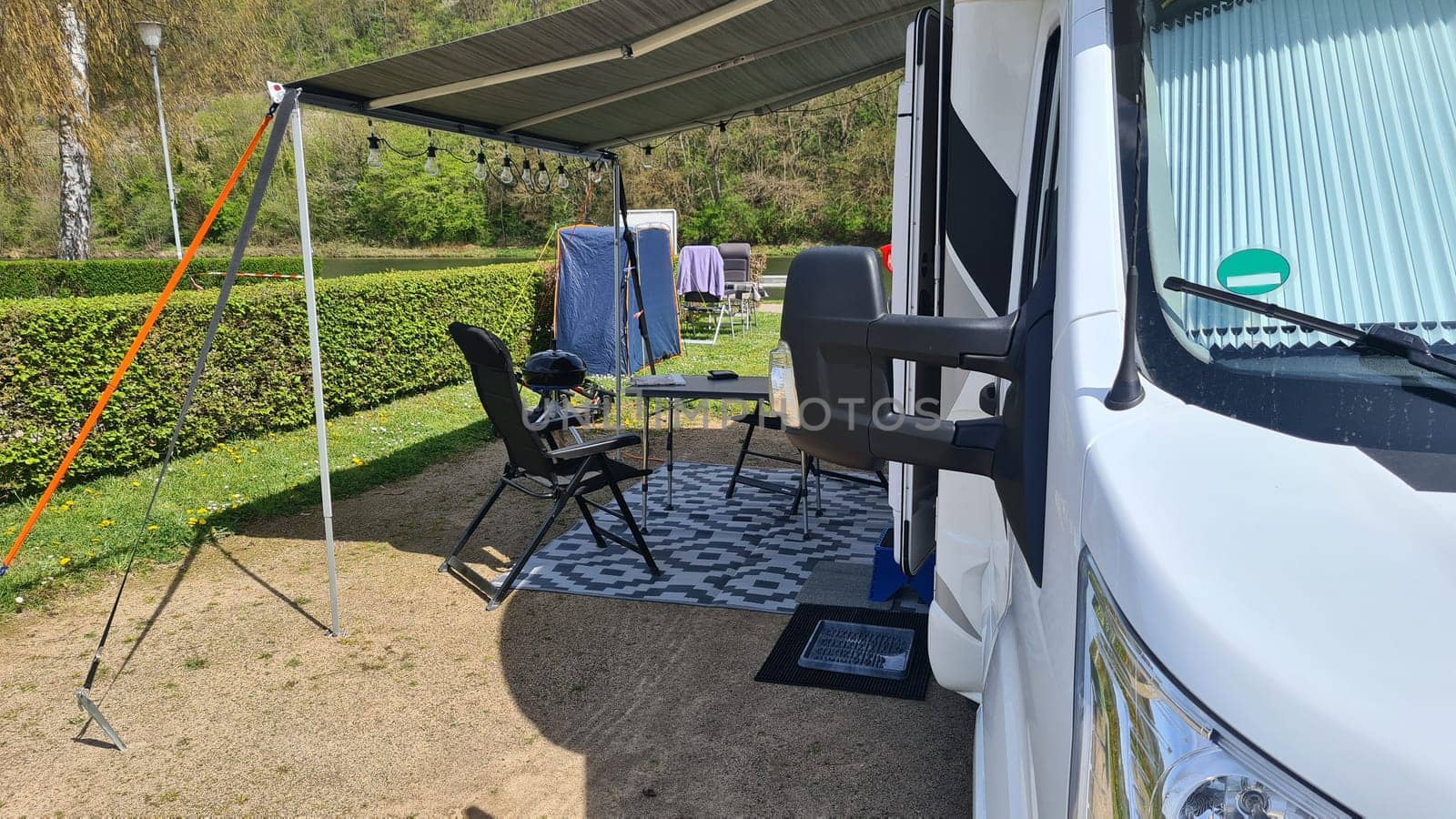 Campervan with awning and air awning and camping table with chairs at campsite