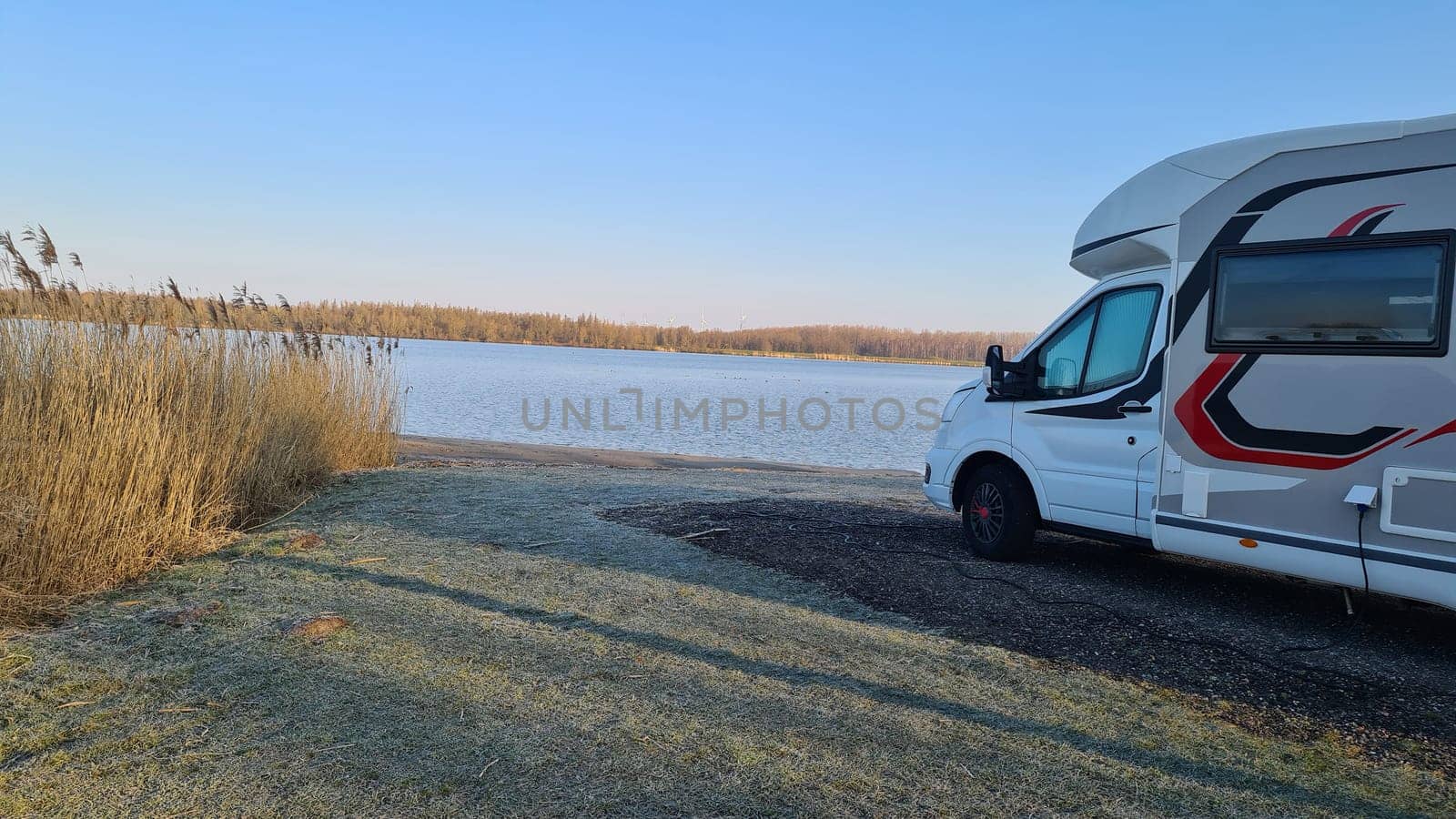 Autumn RV camping. Modern camper van in the late sunny autumn afternoon. Picturesque RV Park.