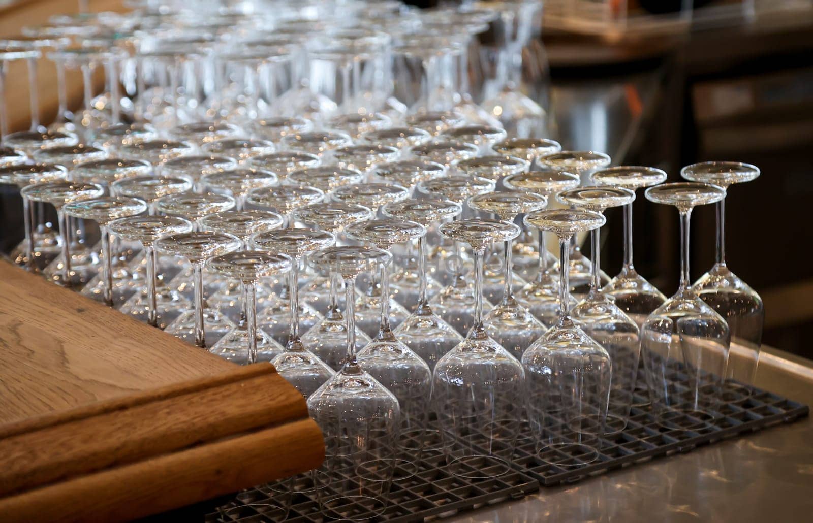 Many clean wine glasses are waiting at the counter to be filled.