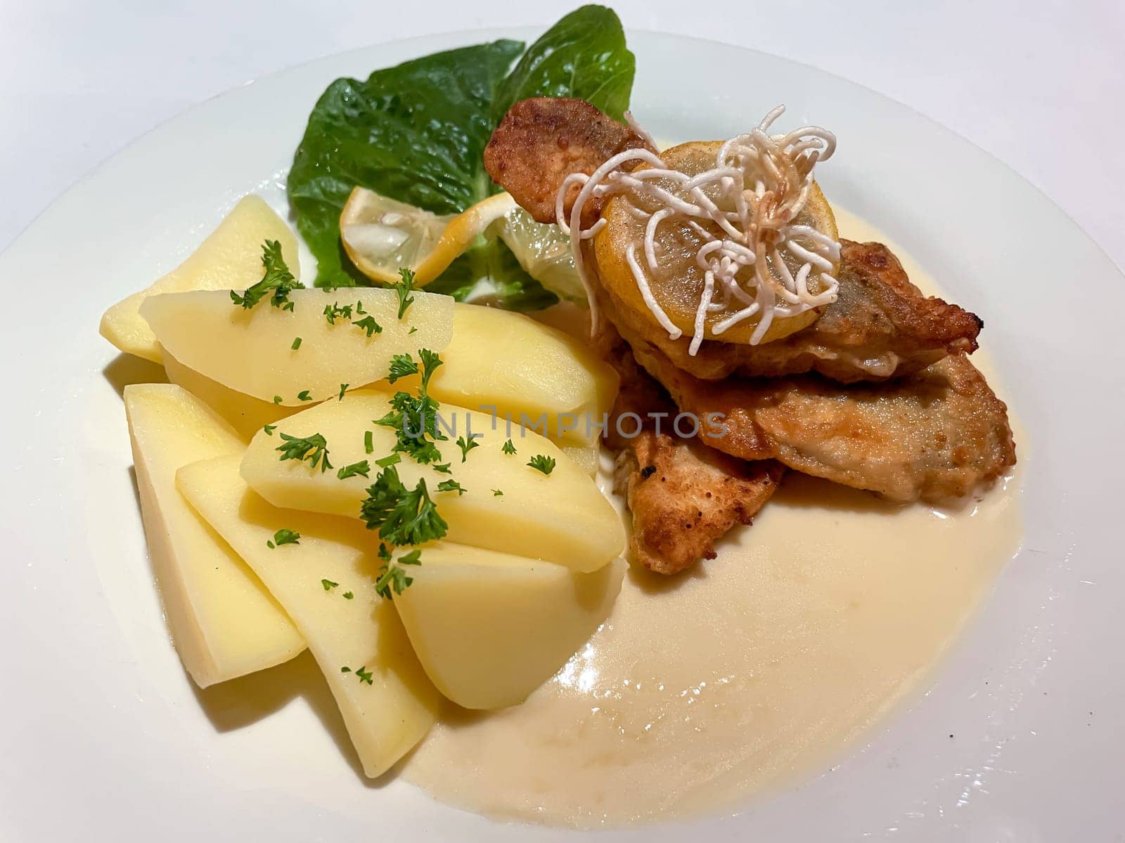 A plate of fried pike perch fillet, with potatoes and lemon.