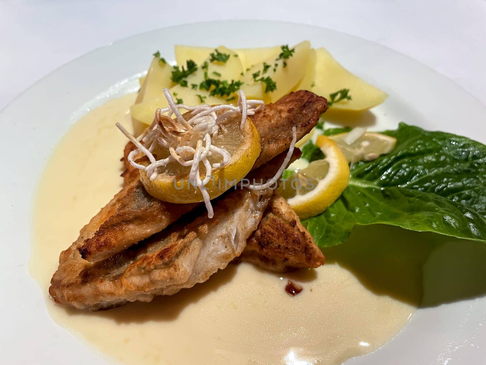 A plate of fried pike perch fillet, with potatoes and lemon.