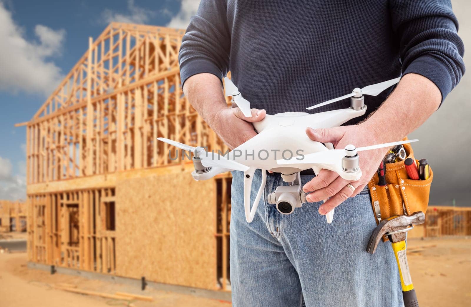 Construction Worker and Drone Pilot With Toolbelt Holding Drone At Construction Site.